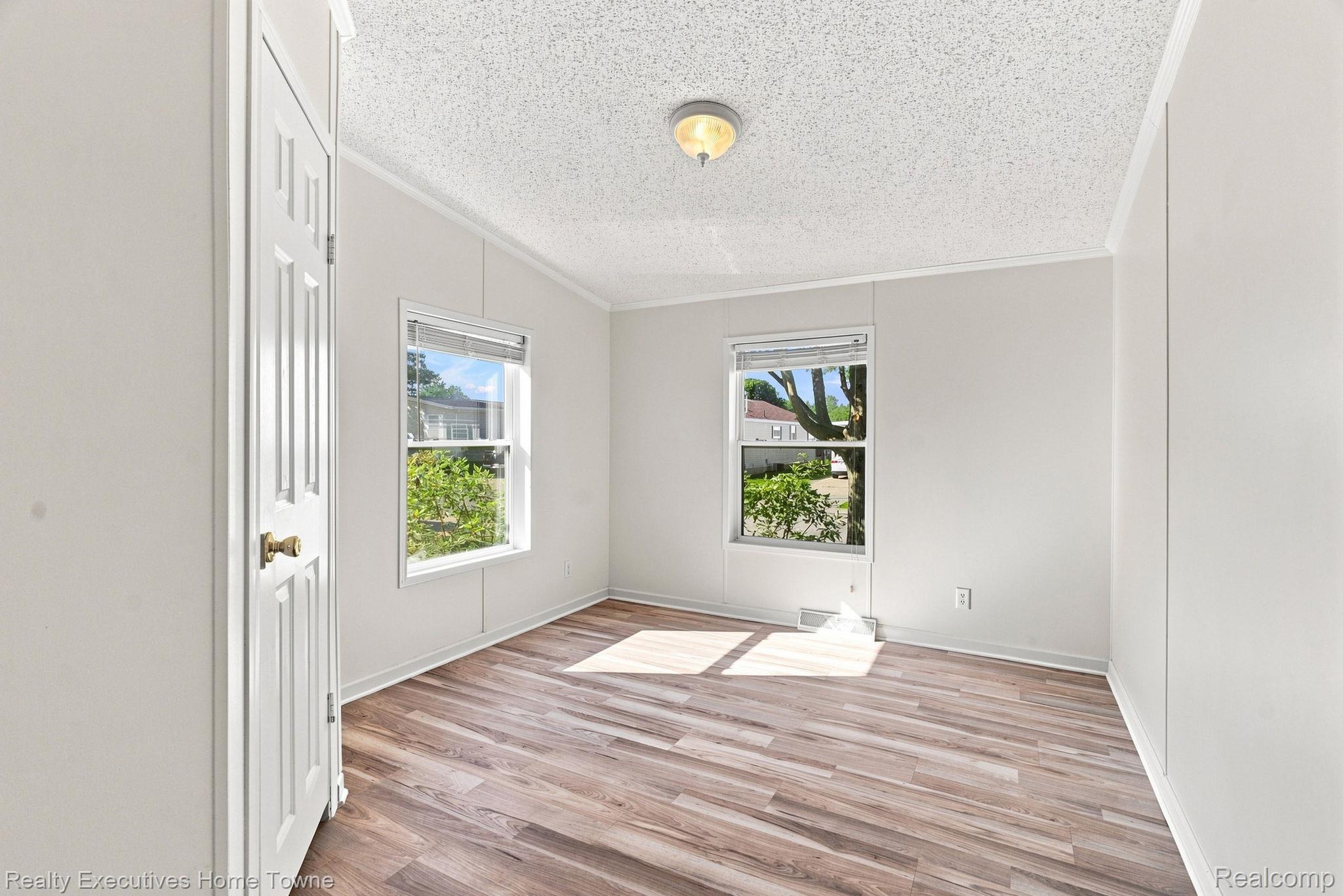 Vacant room with two windows and wood-look plank flooring.