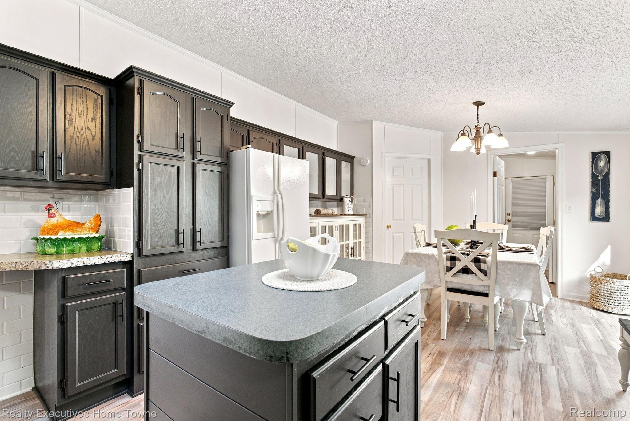 Kitchen with dark wood cabinets, a gray stone island, and an adjoining dining area.