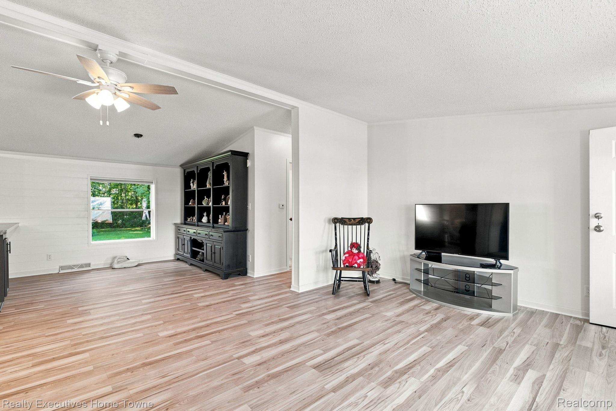 Living room with light wood-look floors, a dark display cabinet, and a television.