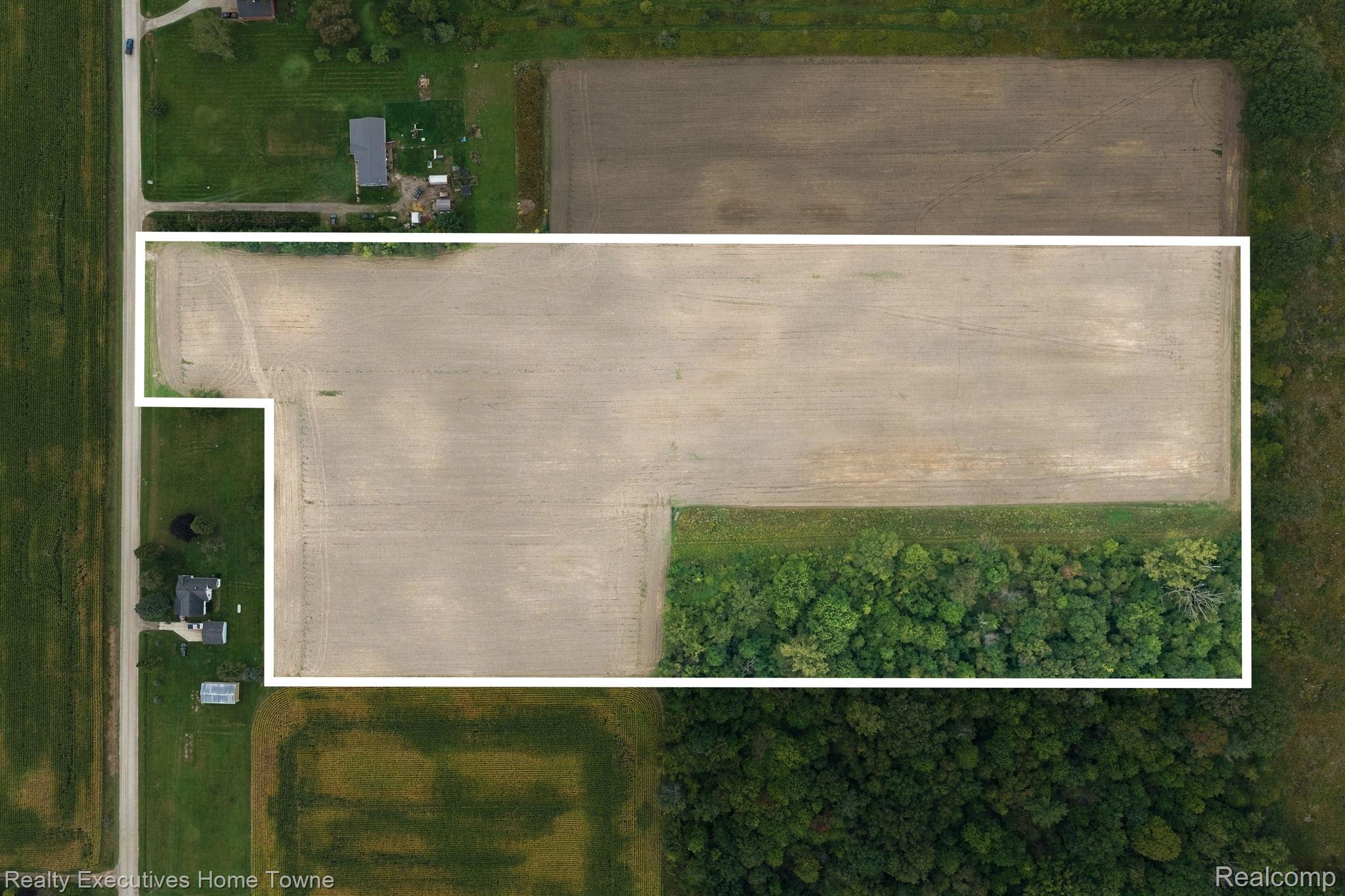 Aerial view of a rural parcel outlined in white, with open fields and woods.