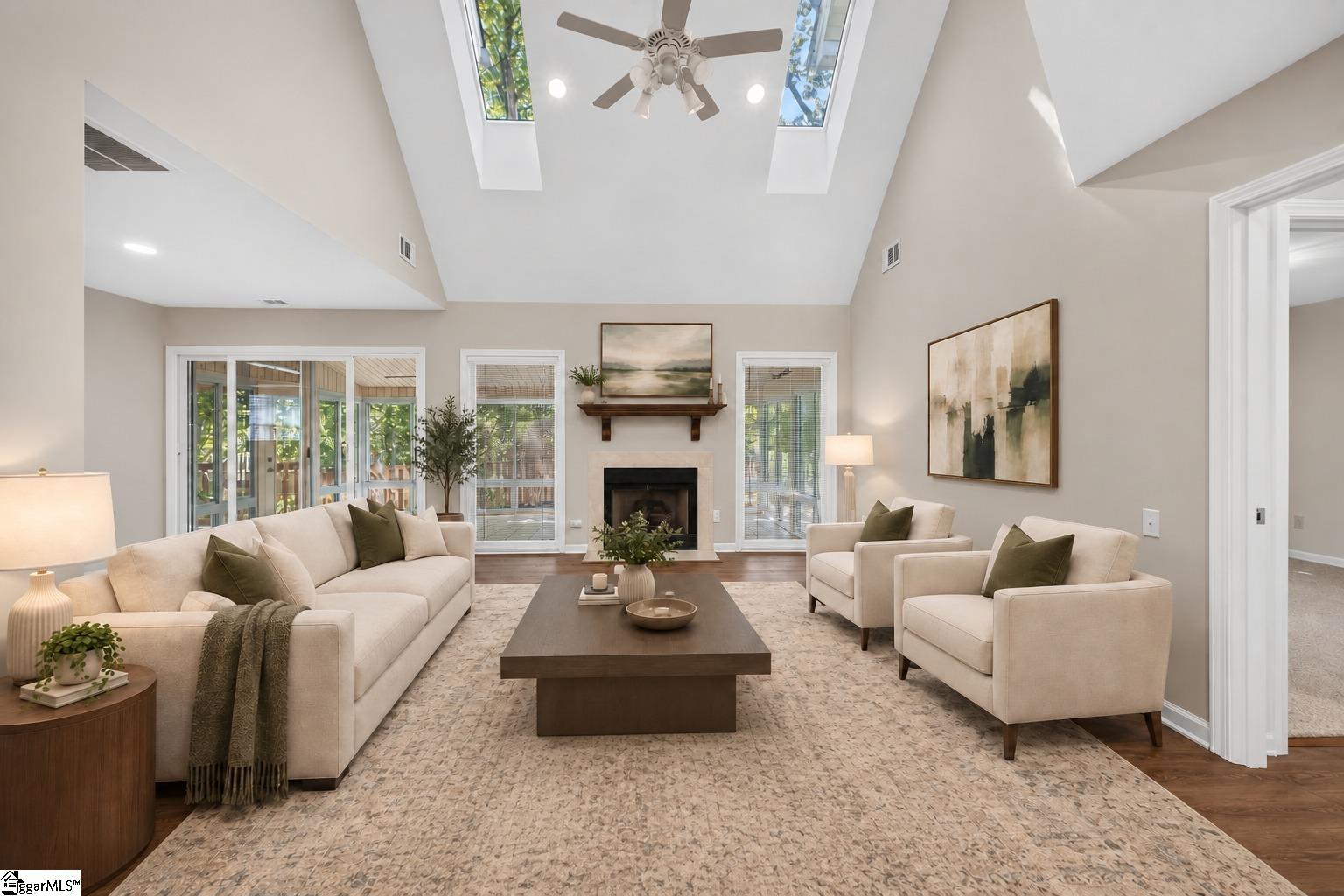 Staged living room with vaulted skylit ceiling, fireplace, and glass doors to a screened porch.