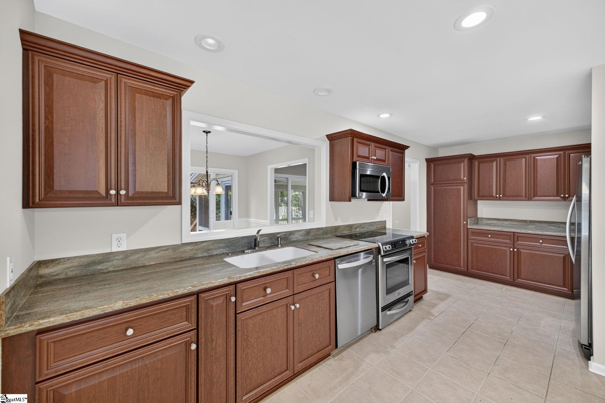 Kitchen with cherry cabinets, stone countertops, and stainless steel appliances.