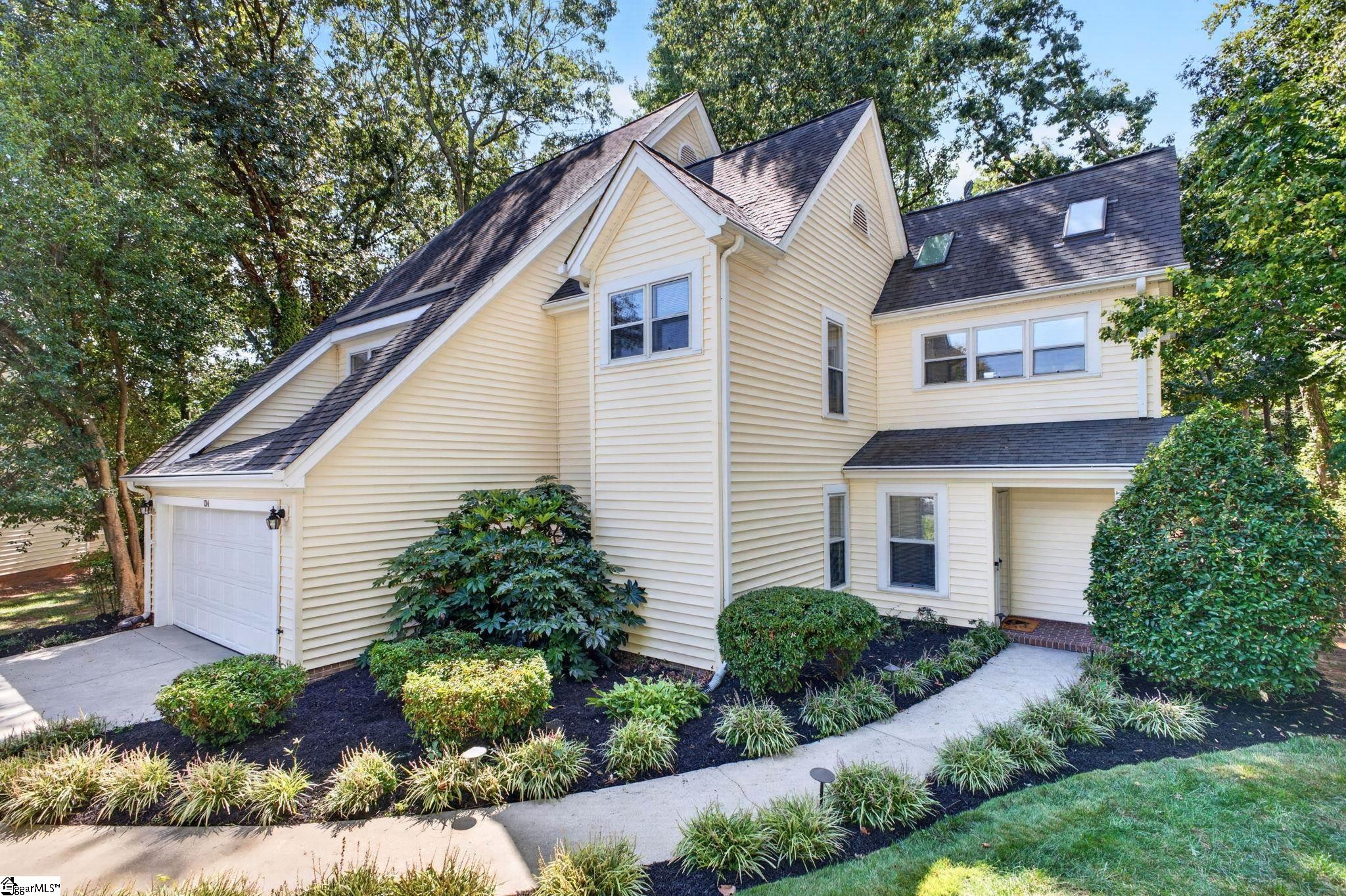 Cream-sided multi-gabled house with an attached garage and landscaped front walk.
