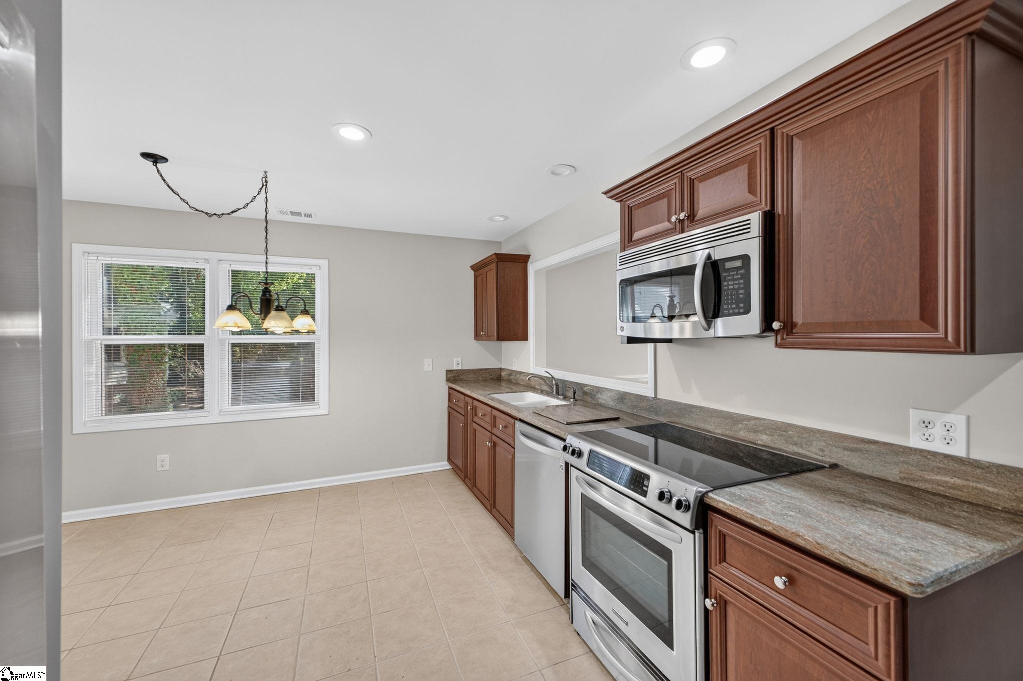 Kitchen with reddish-brown cabinets, granite counters, and stainless steel appliances.