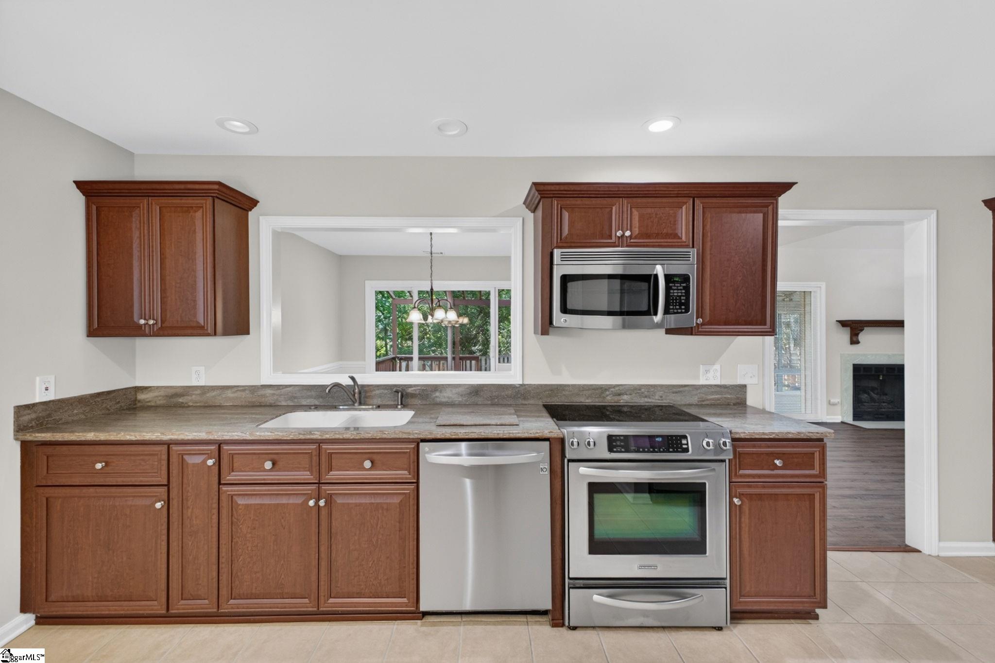 Kitchen with reddish-brown cabinets, granite countertops, and stainless steel appliances.