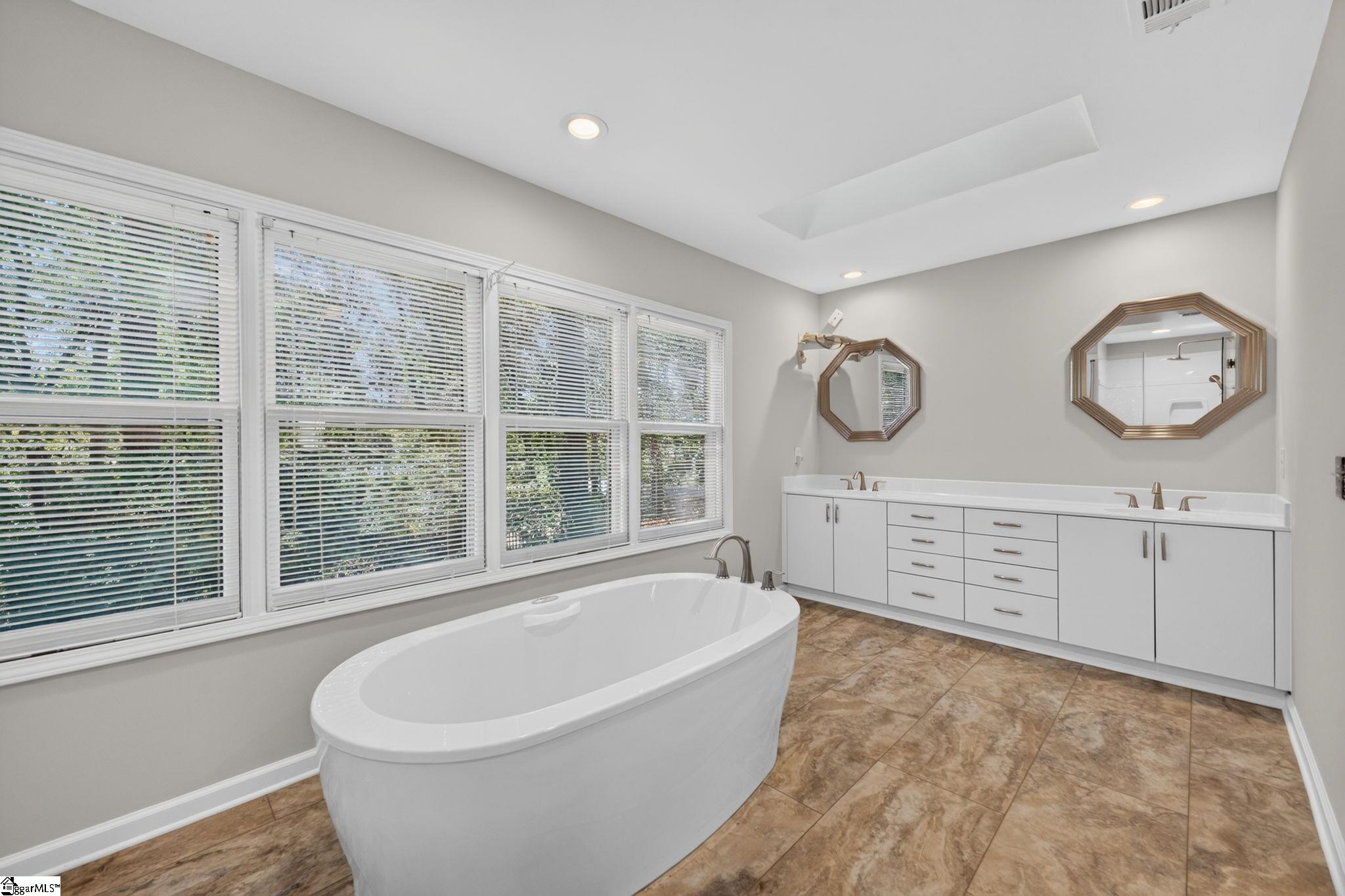 Primary bathroom with a freestanding soaking tub, double vanity, and large windows.