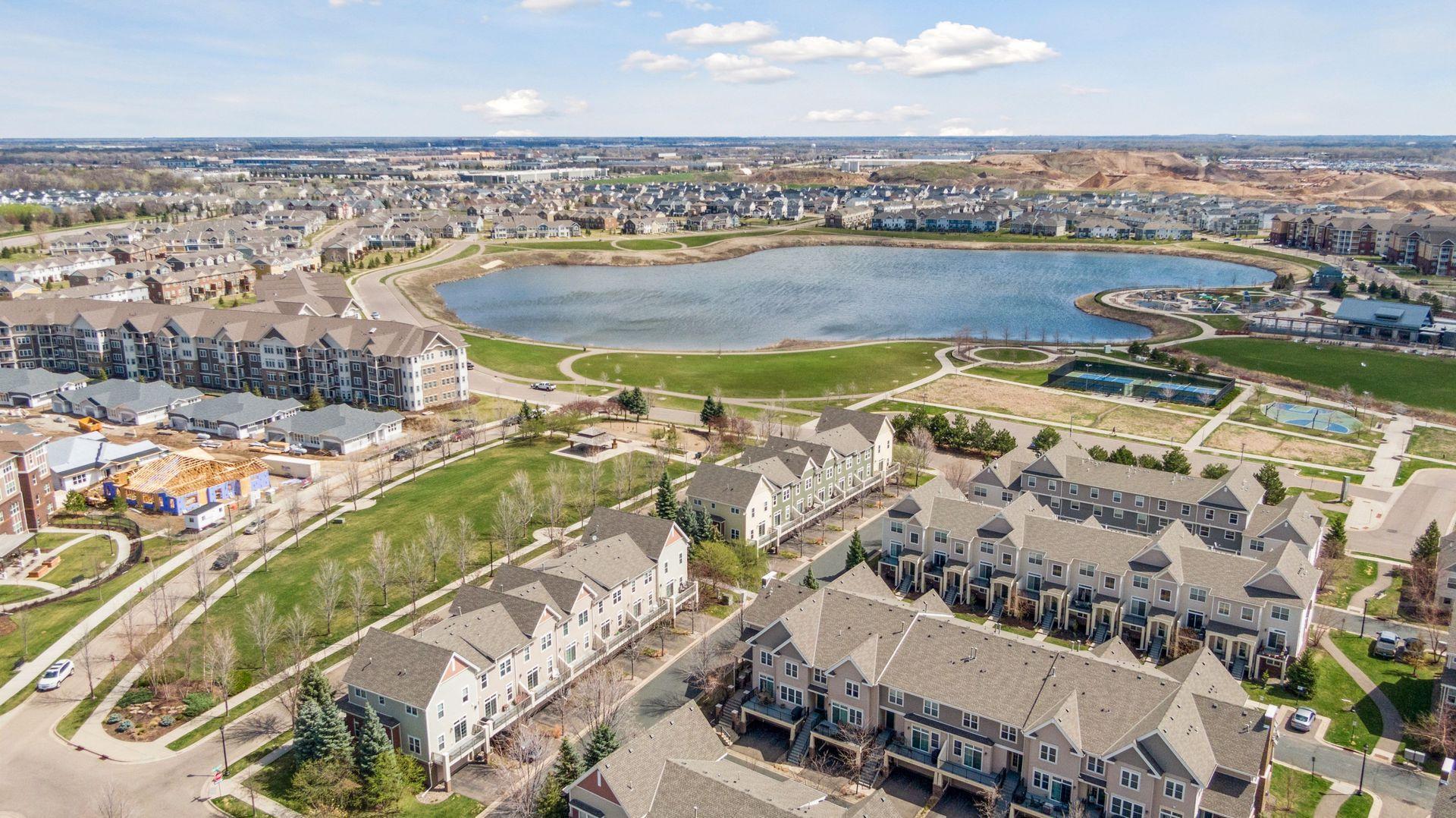 Aerial view of a neighborhood around a lake, with walking paths and recreation courts.