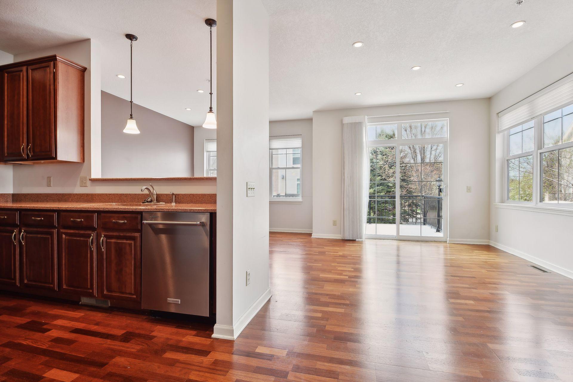 Open kitchen and living area with dark wood cabinets, hardwood floors, and sliding balcony doors.