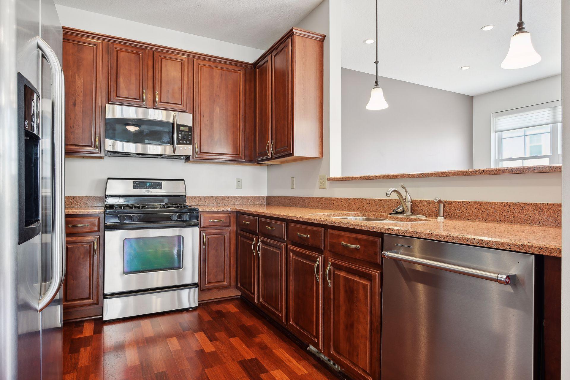 Kitchen with cherry cabinets, granite counters, stainless steel appliances, and hardwood floors.