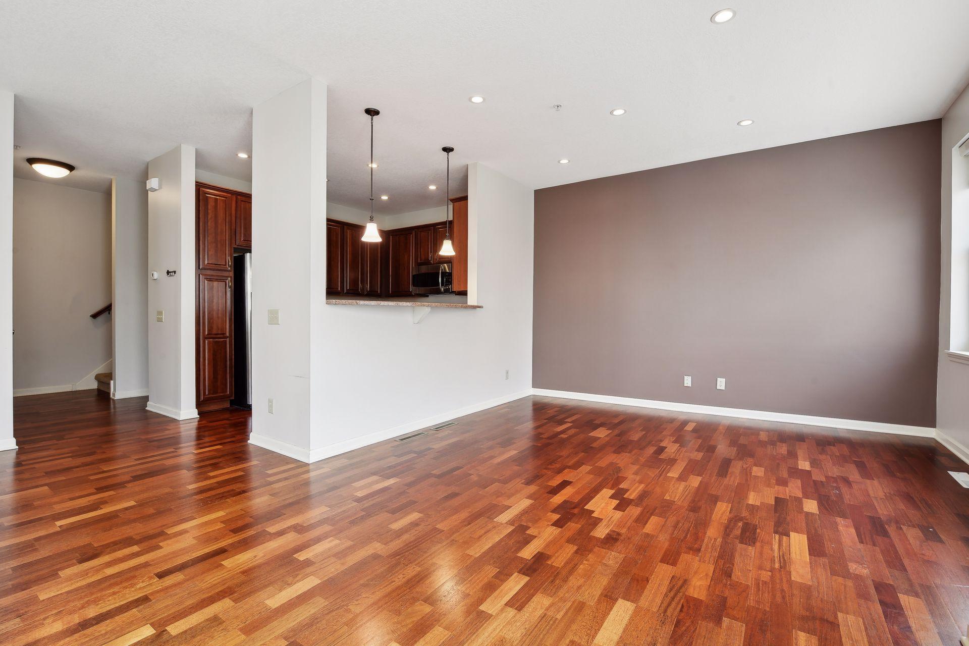 Vacant living area with hardwood floors, mauve accent wall, and kitchen pass-through.