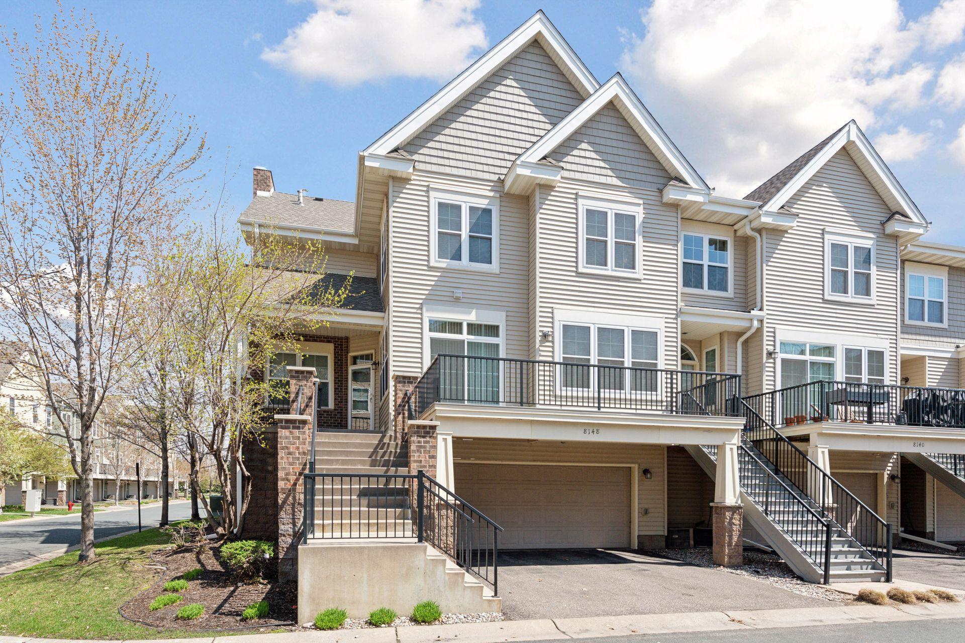 Townhouse exterior with a raised balcony, exterior stairs, and attached garage.