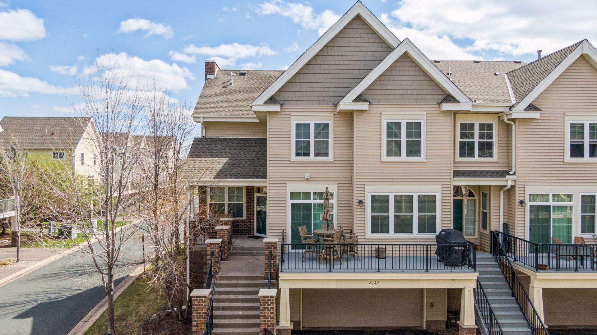 Townhouse rear with a raised patio, outdoor dining set, grill, and exterior stairs.