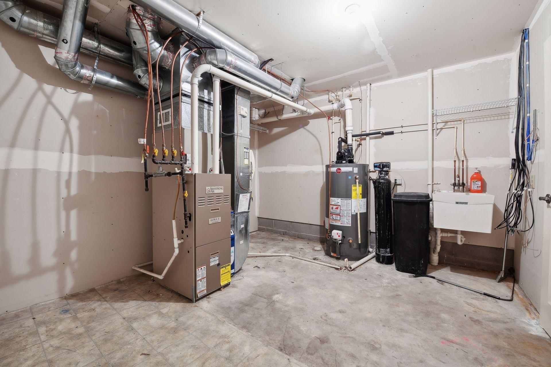 Unfinished utility room with a furnace, exposed ductwork, and a water heater.