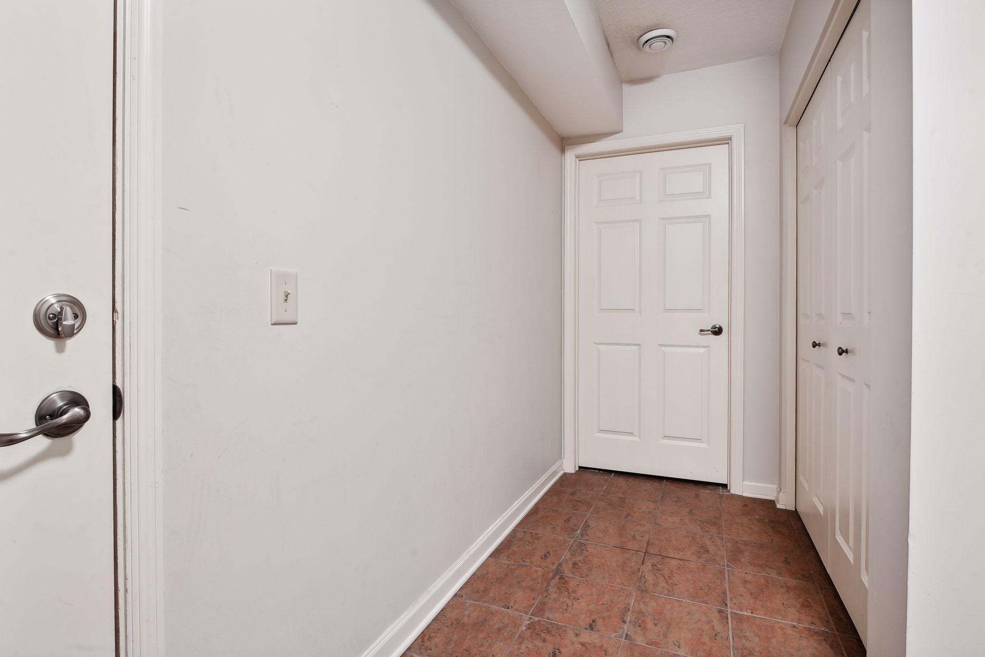 Entry hallway with reddish-brown tile flooring and double closet doors.