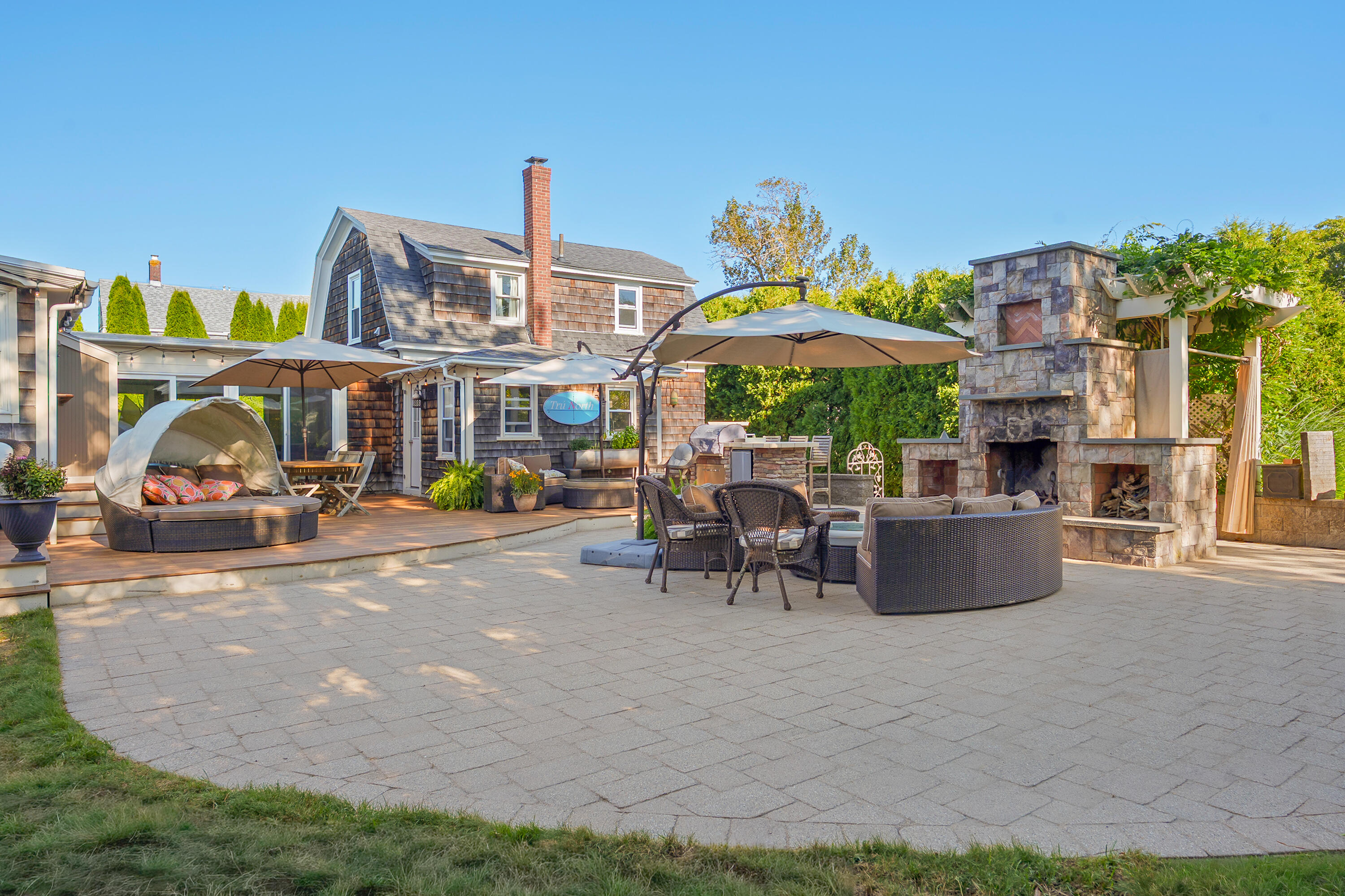 Furnished patio with a large stone fireplace, umbrellas, and a cushioned outdoor daybed.