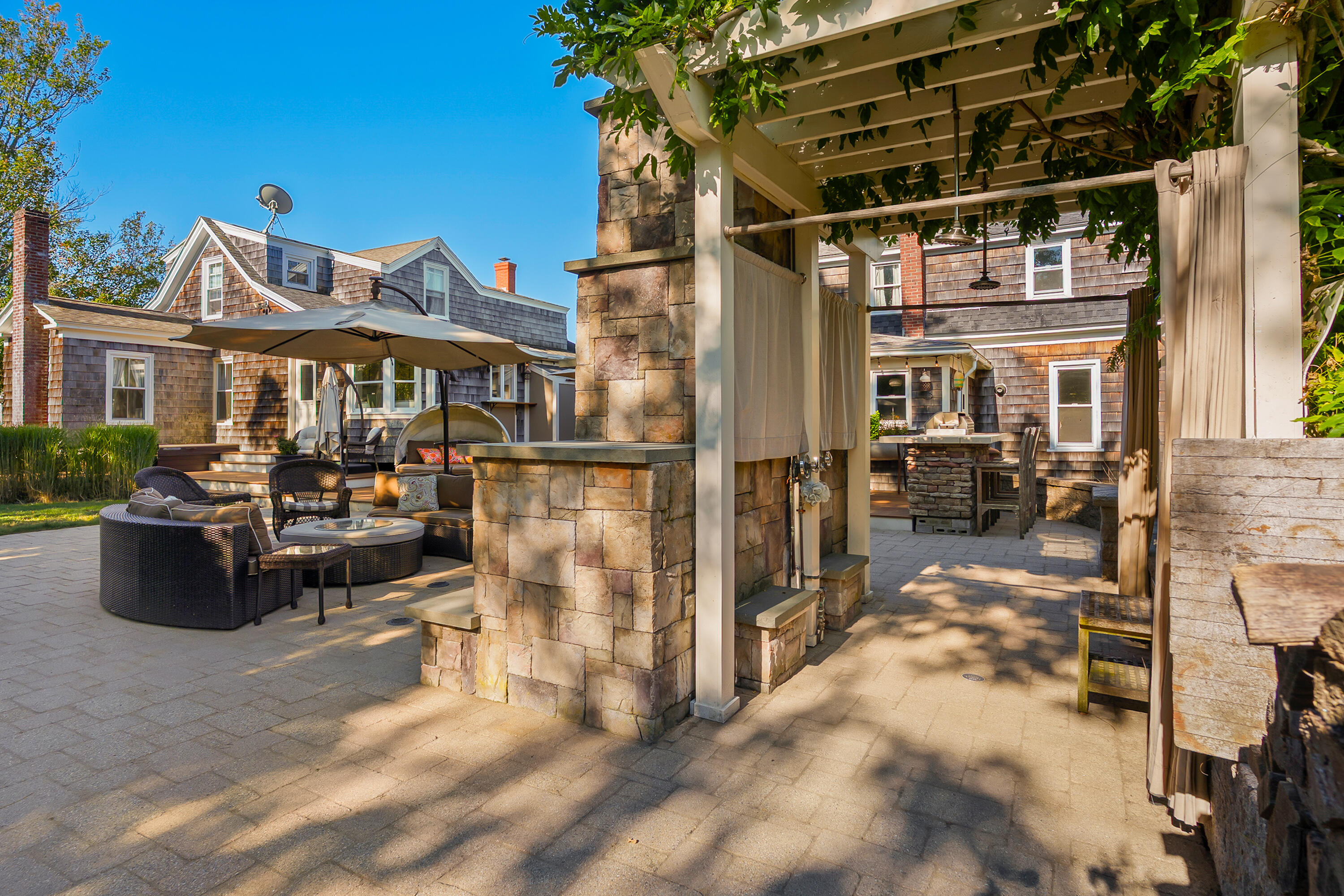 Stone patio with a pergola, outdoor fireplace, lounge seating, and dining counter