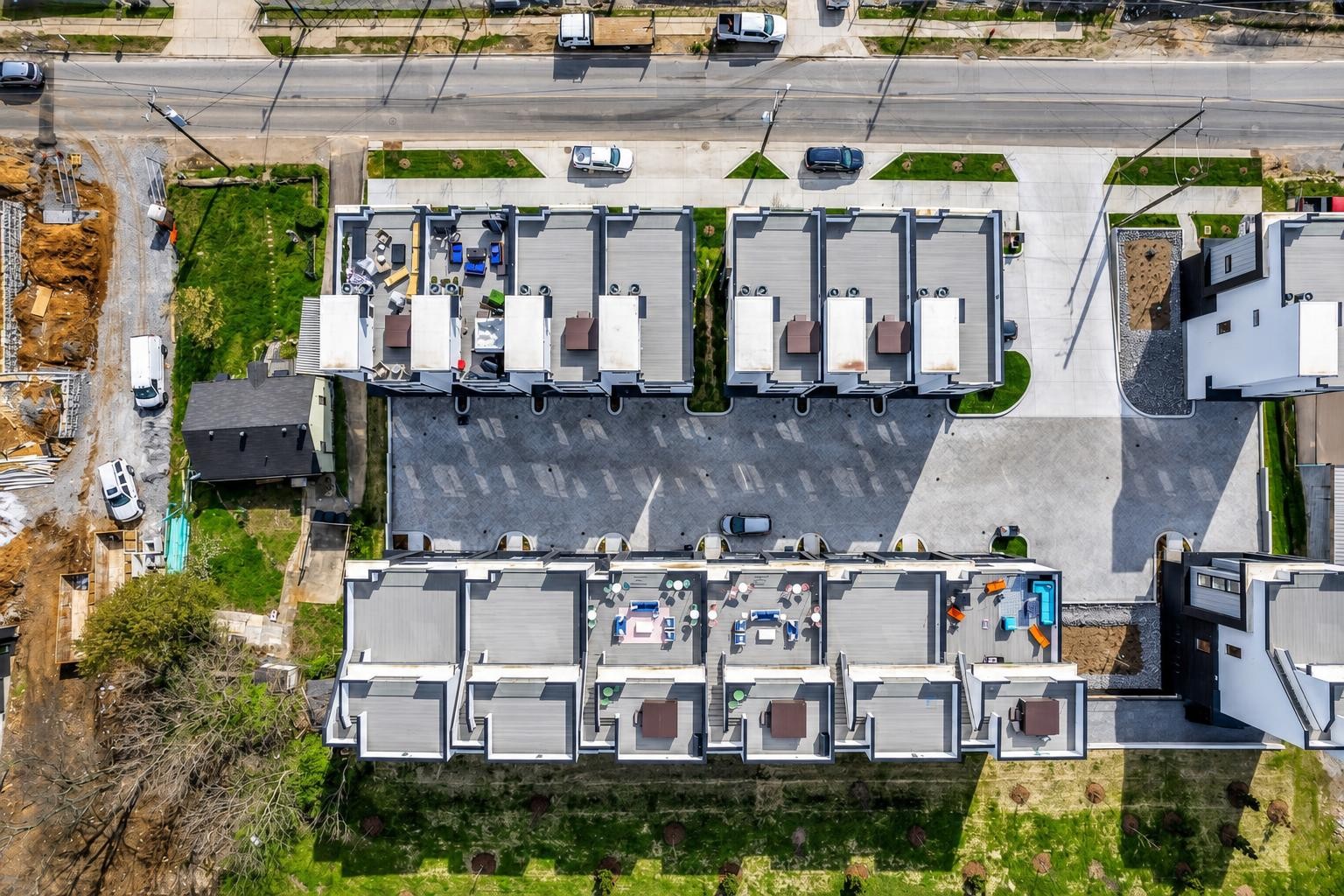 Aerial view of attached townhomes around a paved courtyard, with furnished rooftop patios.