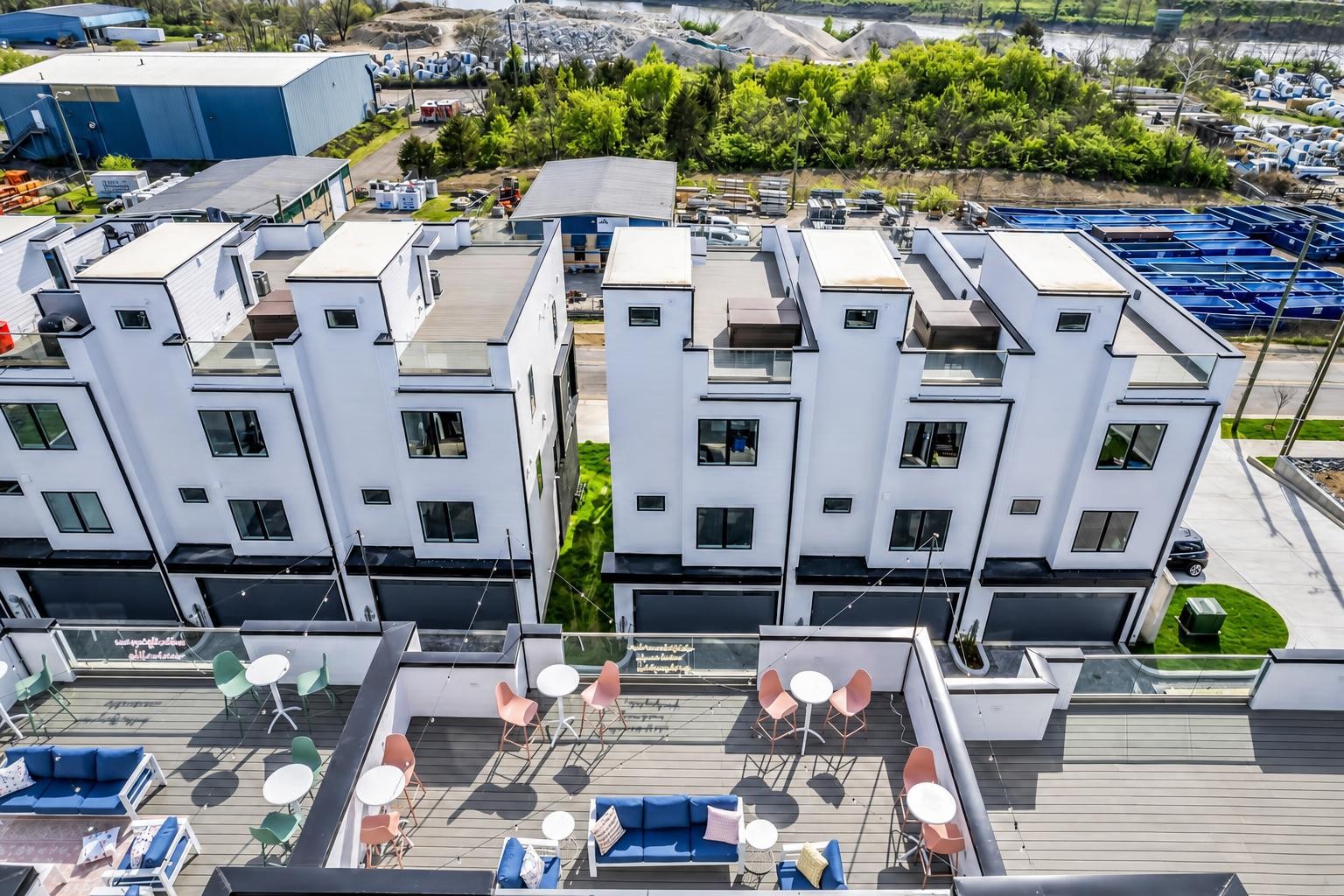 Aerial view of modern townhomes with rooftop decks furnished with colorful patio seating.