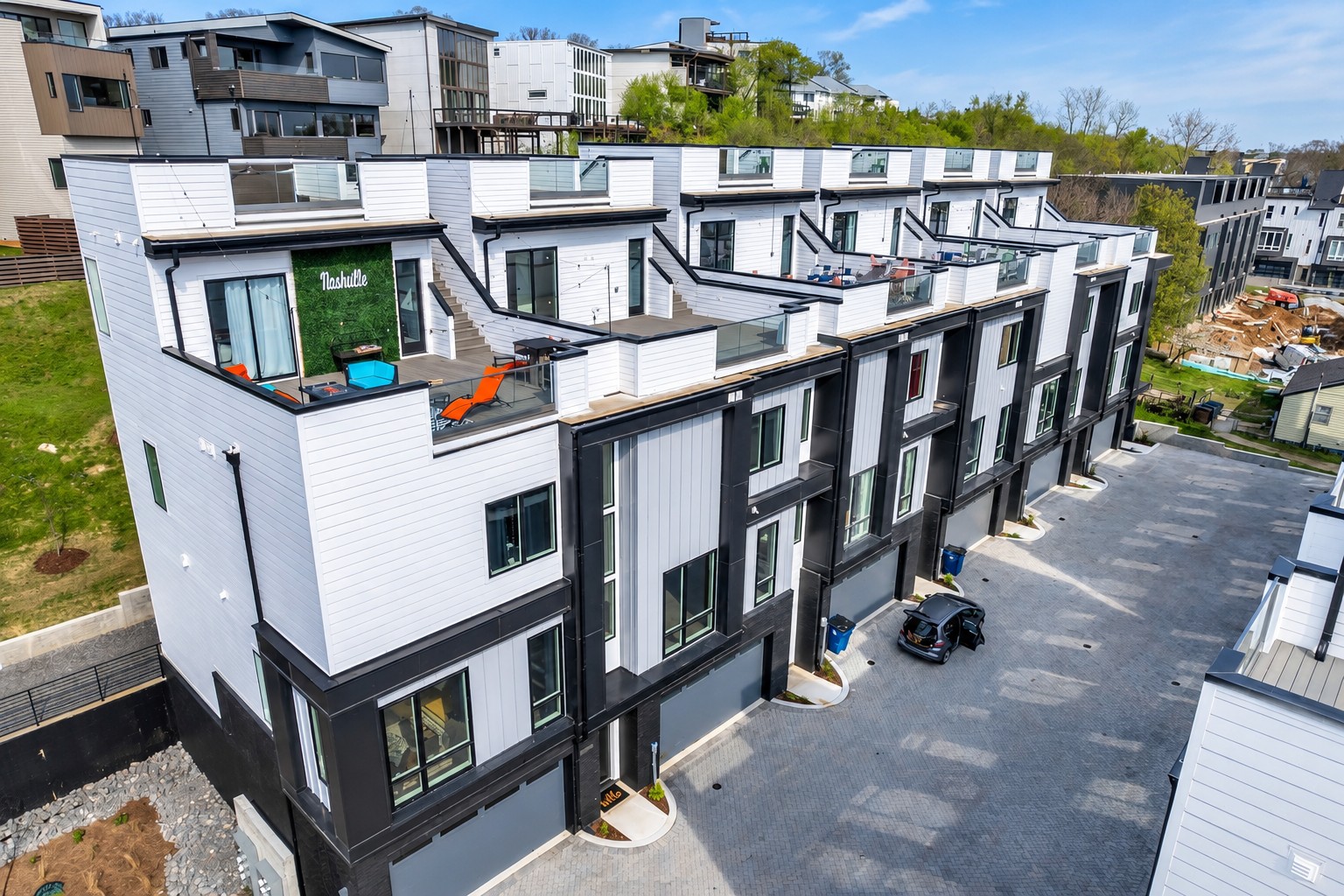 Aerial view of modern townhomes with rooftop terraces and a paved parking area.