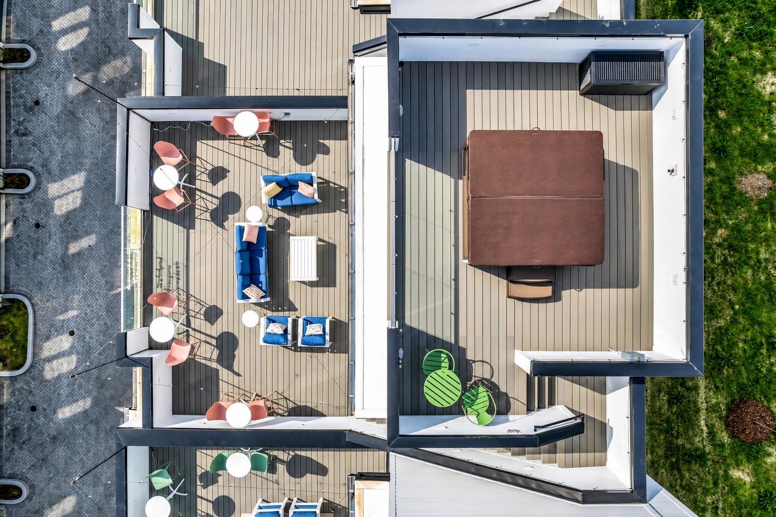 Rooftop deck with blue lounge seating and a square hot tub, viewed from above.