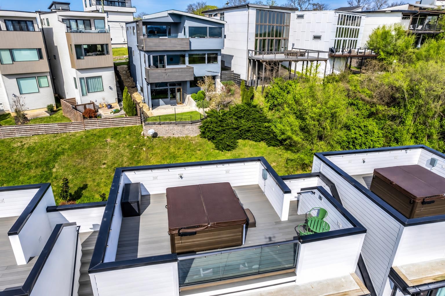 Modern townhouses with rooftop hot tubs overlooking a shared lawn.