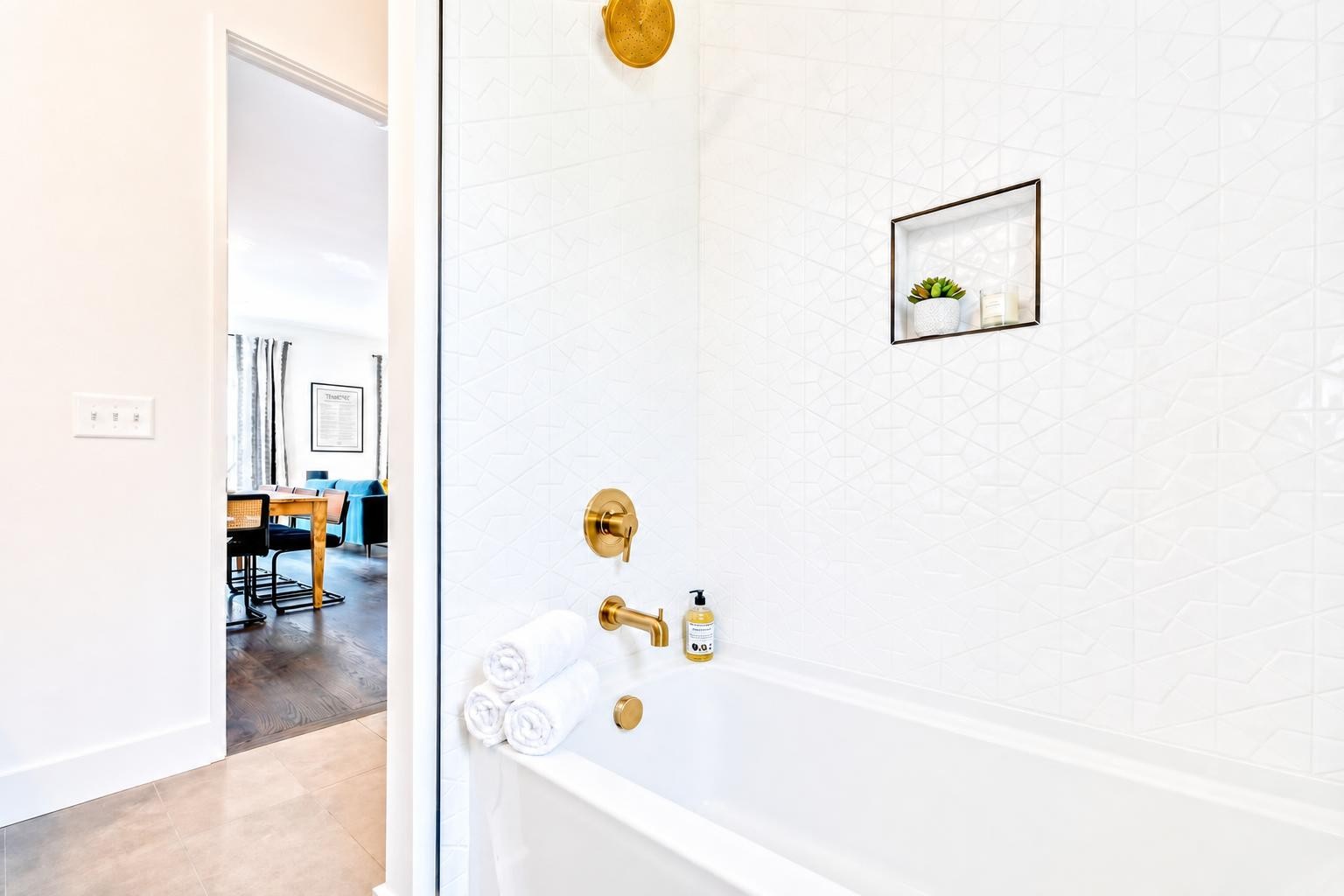 Bathroom with a white tiled bathtub surround, gold fixtures, and a recessed display niche.