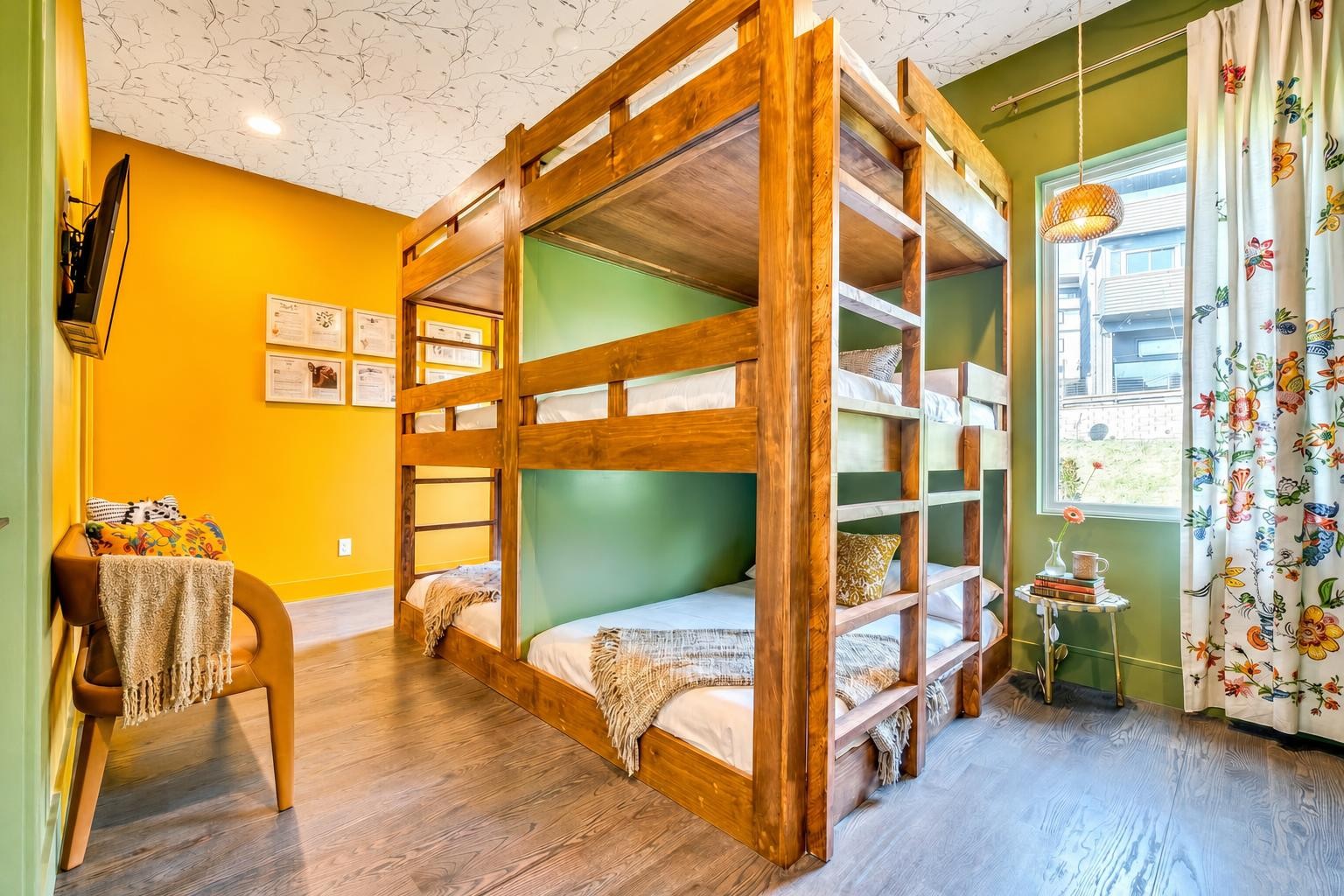 Bedroom with a large wooden bunk bed, green and yellow walls, and floral curtains.
