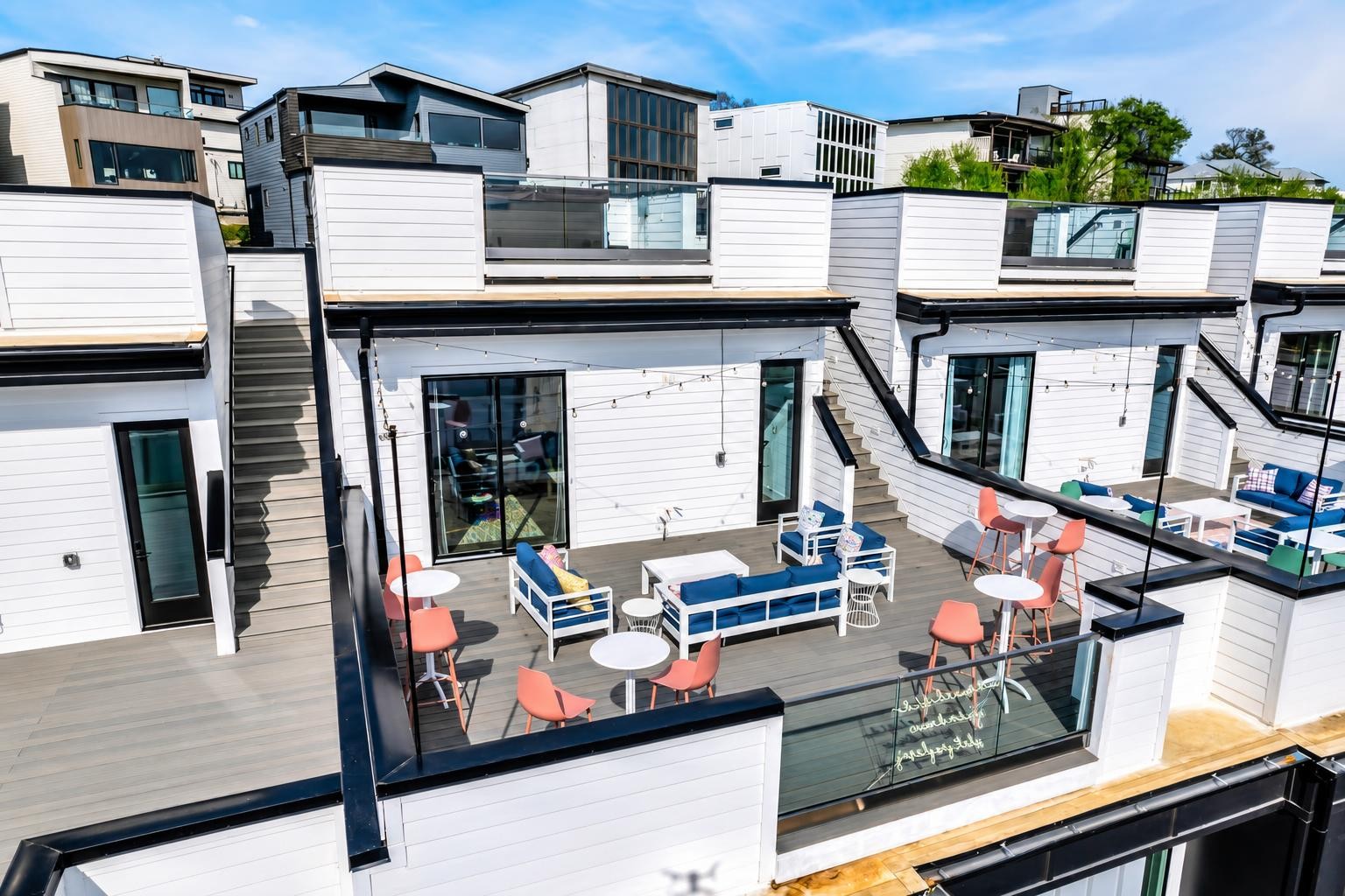 Furnished rooftop terrace with blue-and-white lounge seating, coral chairs, and glass railings.
