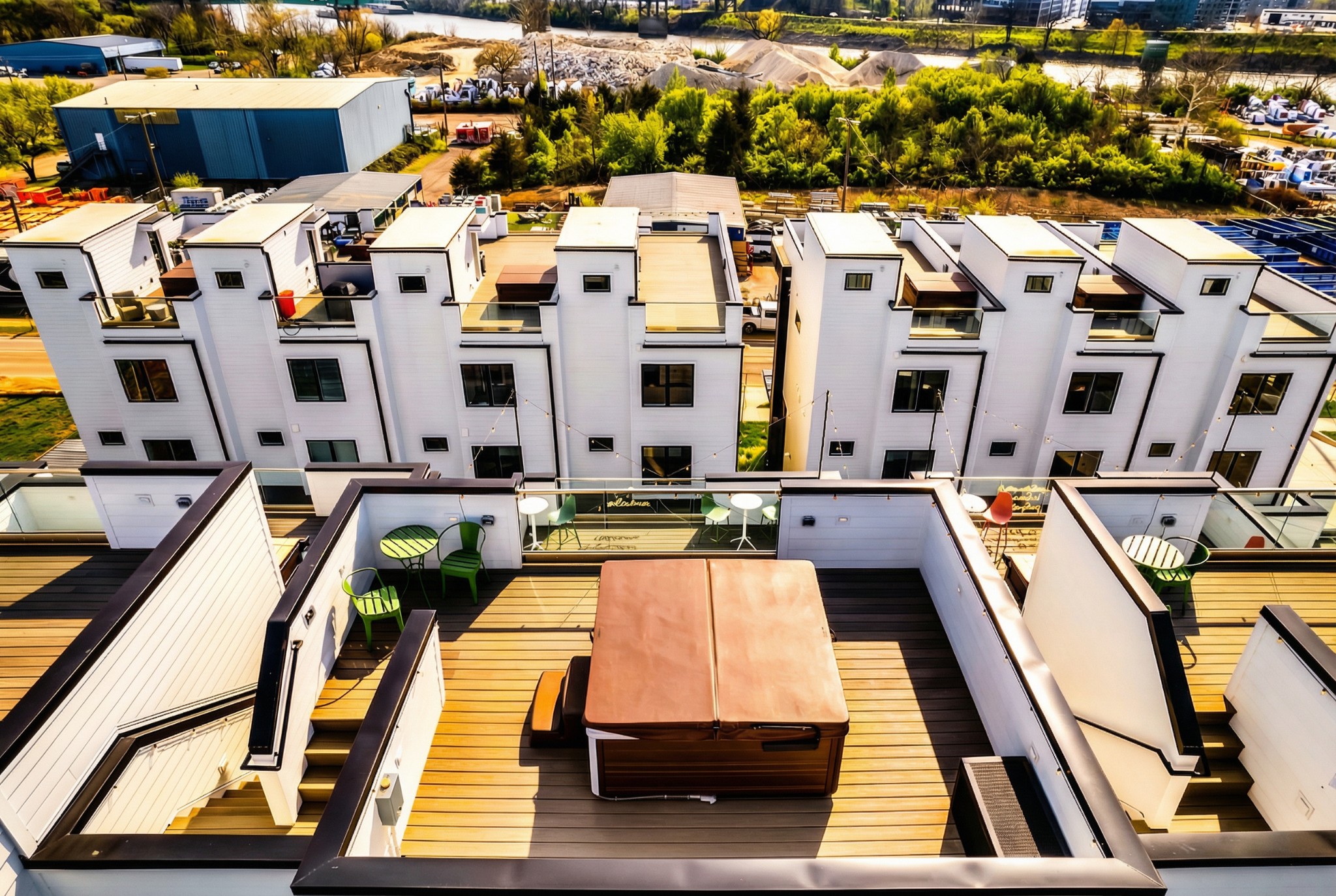 Aerial view of modern townhomes with rooftop decks, outdoor seating, and hot tubs.
