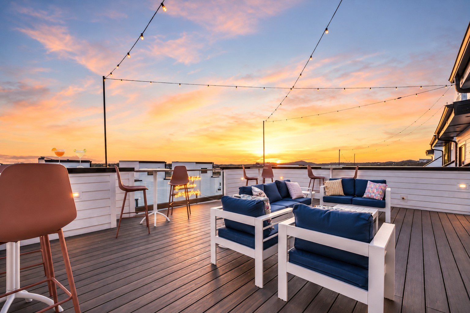 Rooftop deck with navy lounge seating and string lights overlooking the sunset.