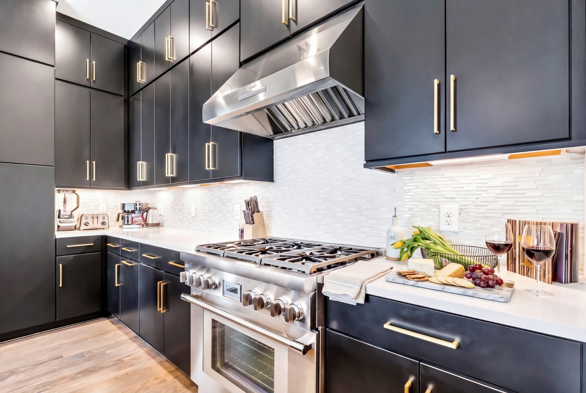 Modern kitchen with dark cabinets, brass hardware, and a large stainless-steel range.