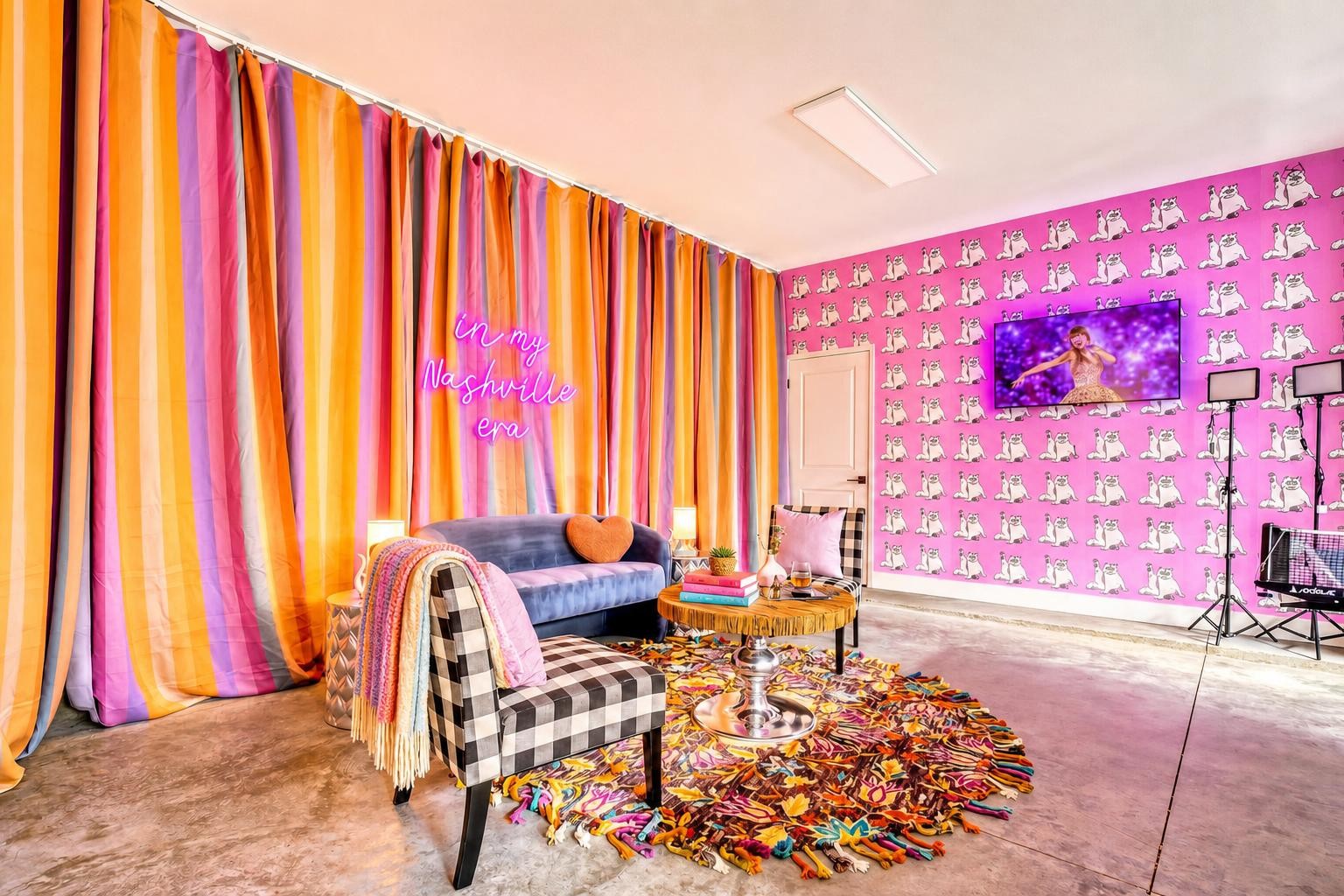 Colorful furnished room with striped curtains, cat wallpaper, a neon sign, sofa, and patterned rug.
