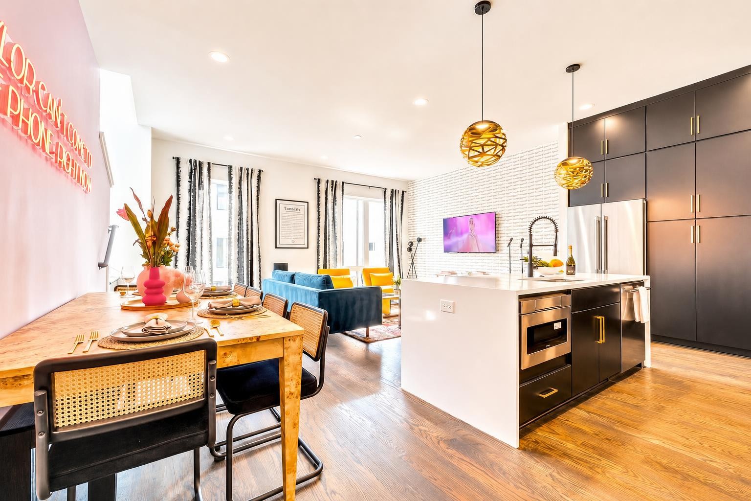 Open-plan kitchen and dining area with dark cabinetry, a white island, and blue living-room seating.
