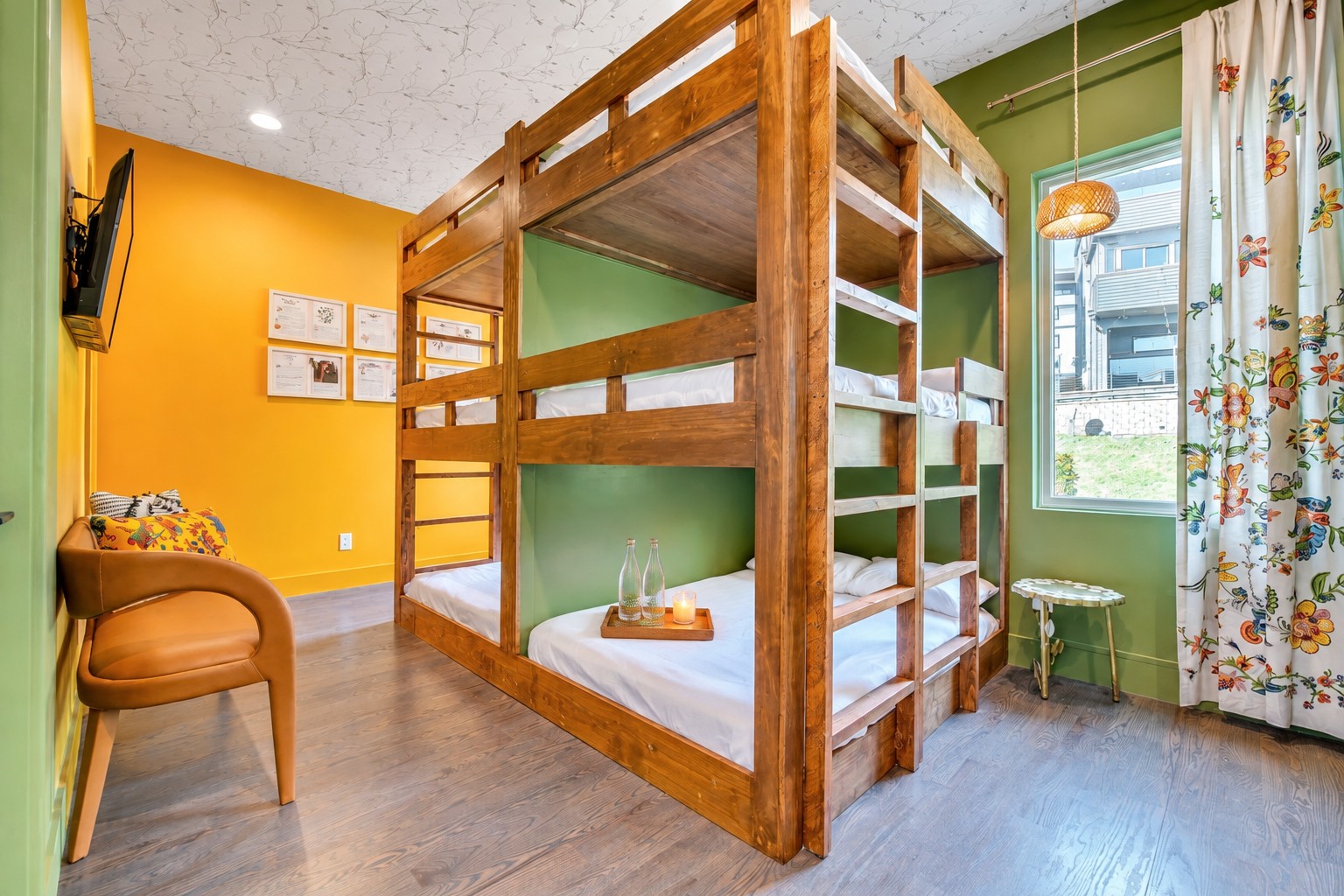 Bedroom with a large wooden bunk bed, green and yellow walls, and a window with floral curtains.