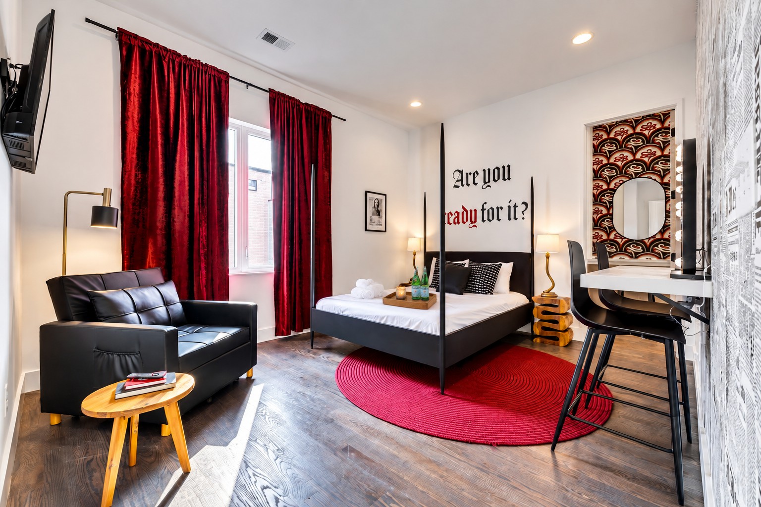 Bedroom with a black four-poster bed, dramatic red curtains, and a matching round red rug.