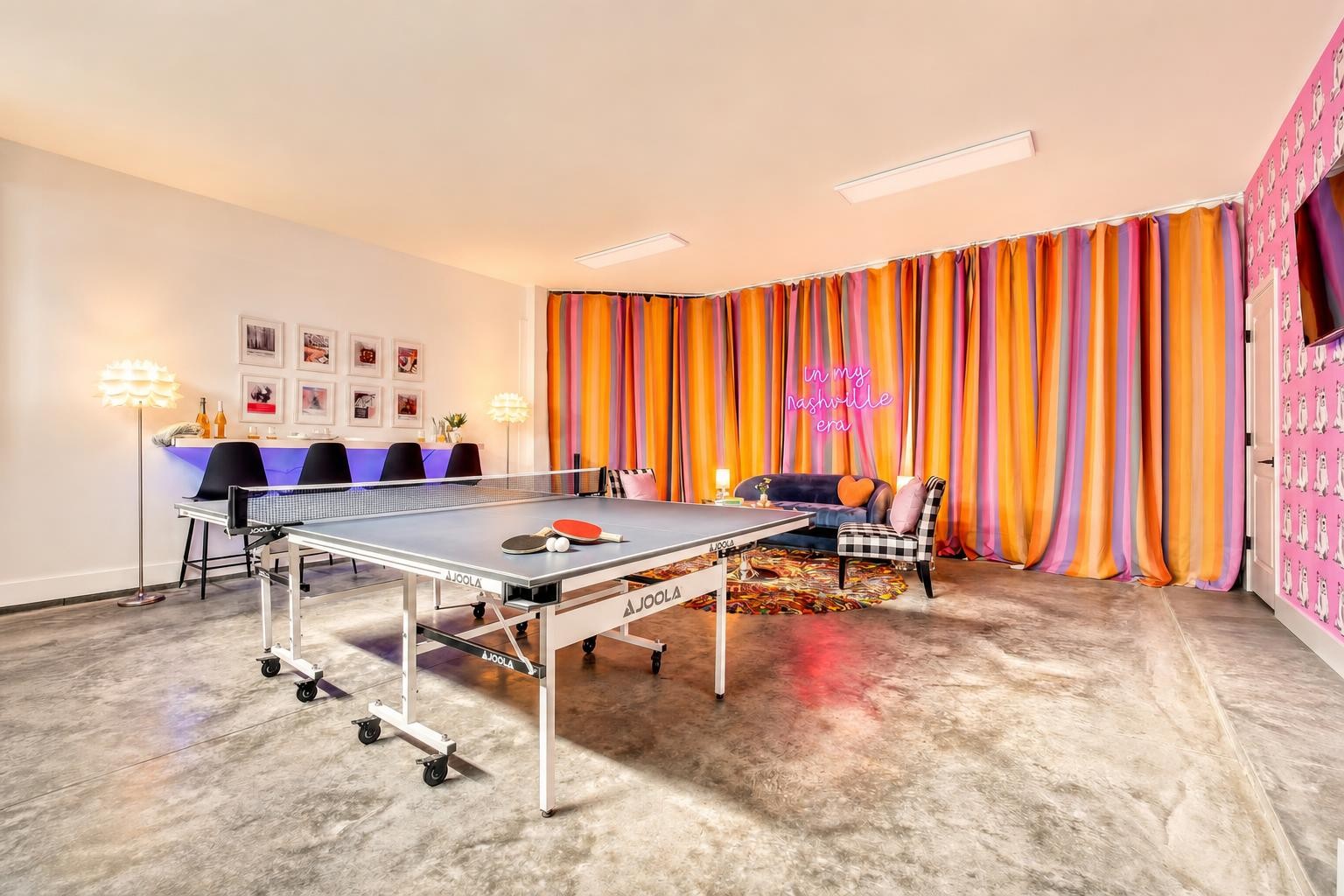 Furnished game room with a ping-pong table, vivid striped curtains, and a neon Nashville sign.