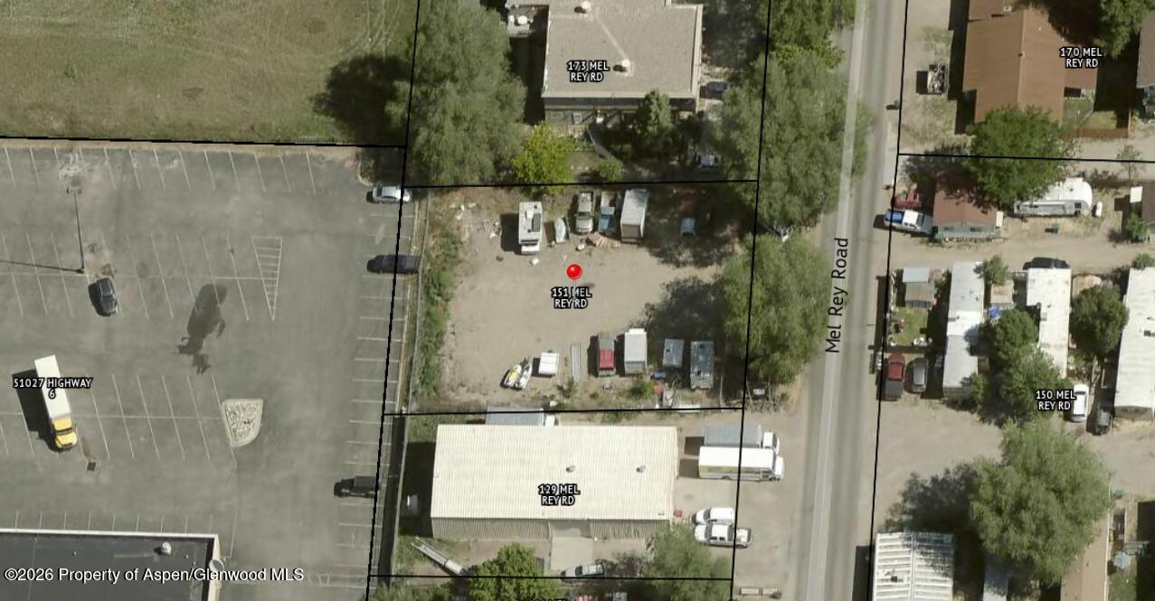 Aerial view of the dirt lot at 151 Mel Rey Road, with parked vehicles and trailers beside the road.