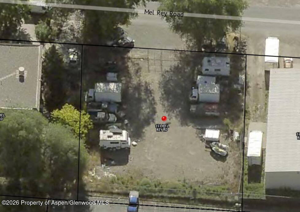 Aerial view of a gravel lot with parked vehicles, trailers, and property boundary lines.