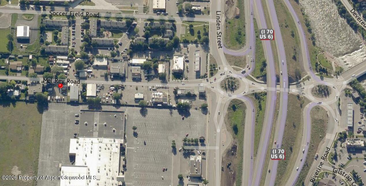 Aerial view of Mel Rey Road, marked with a red pin beside commercial buildings and parking lots.