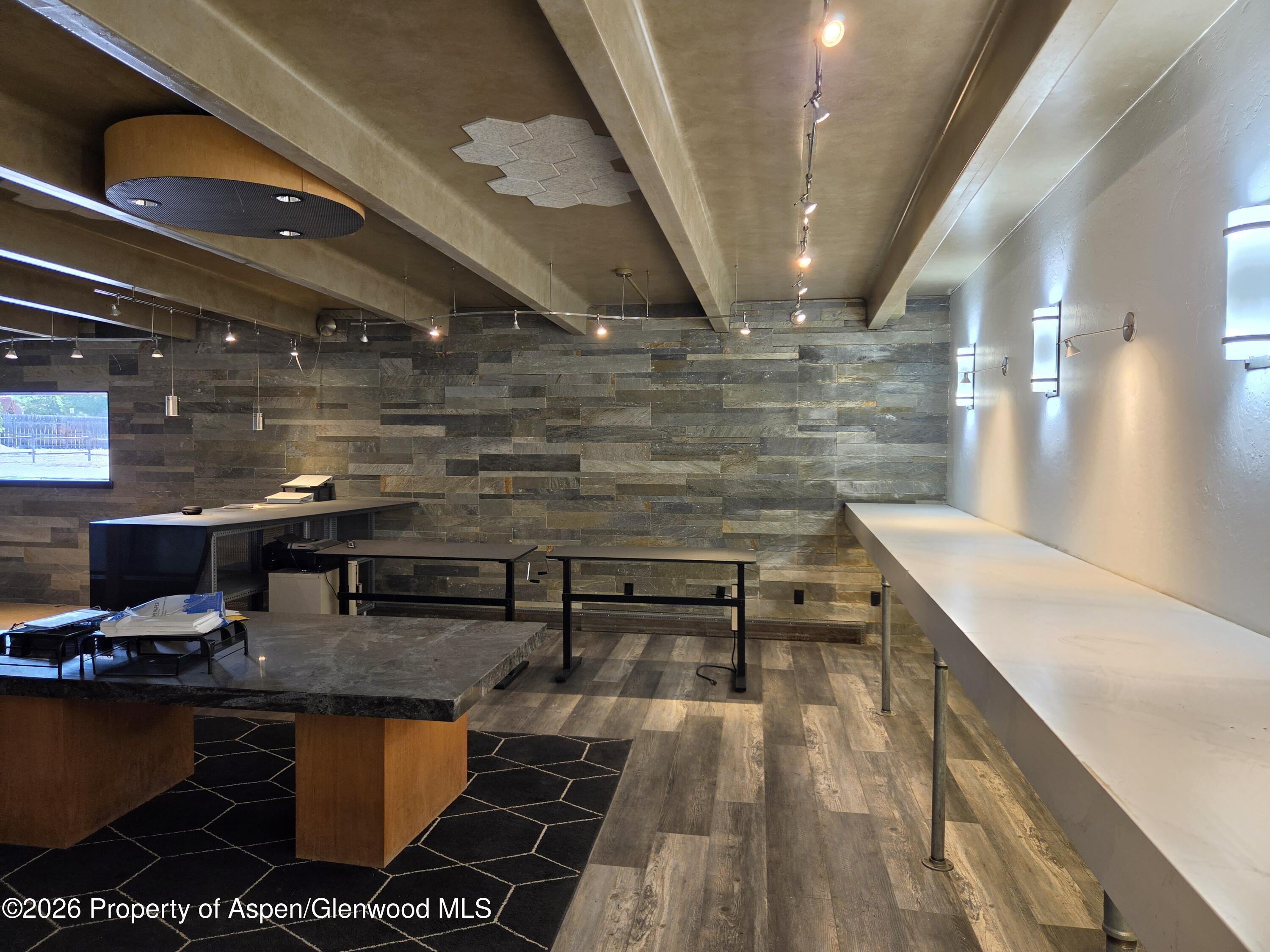 Commercial interior with a long white counter and a dark stone reception counter against a slate wall.