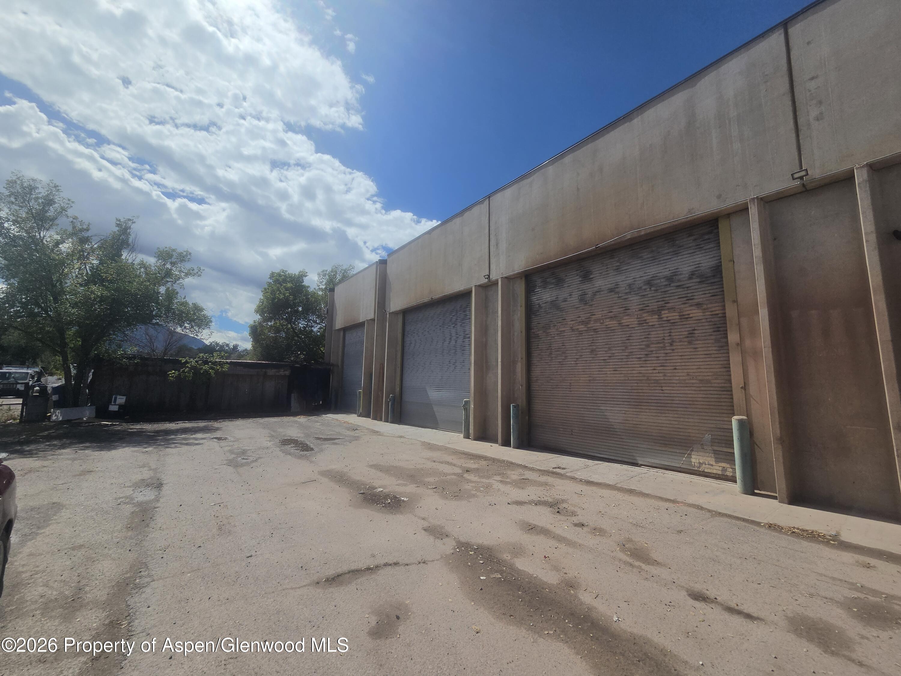 Commercial building with multiple roll-up garage doors facing a paved service yard.