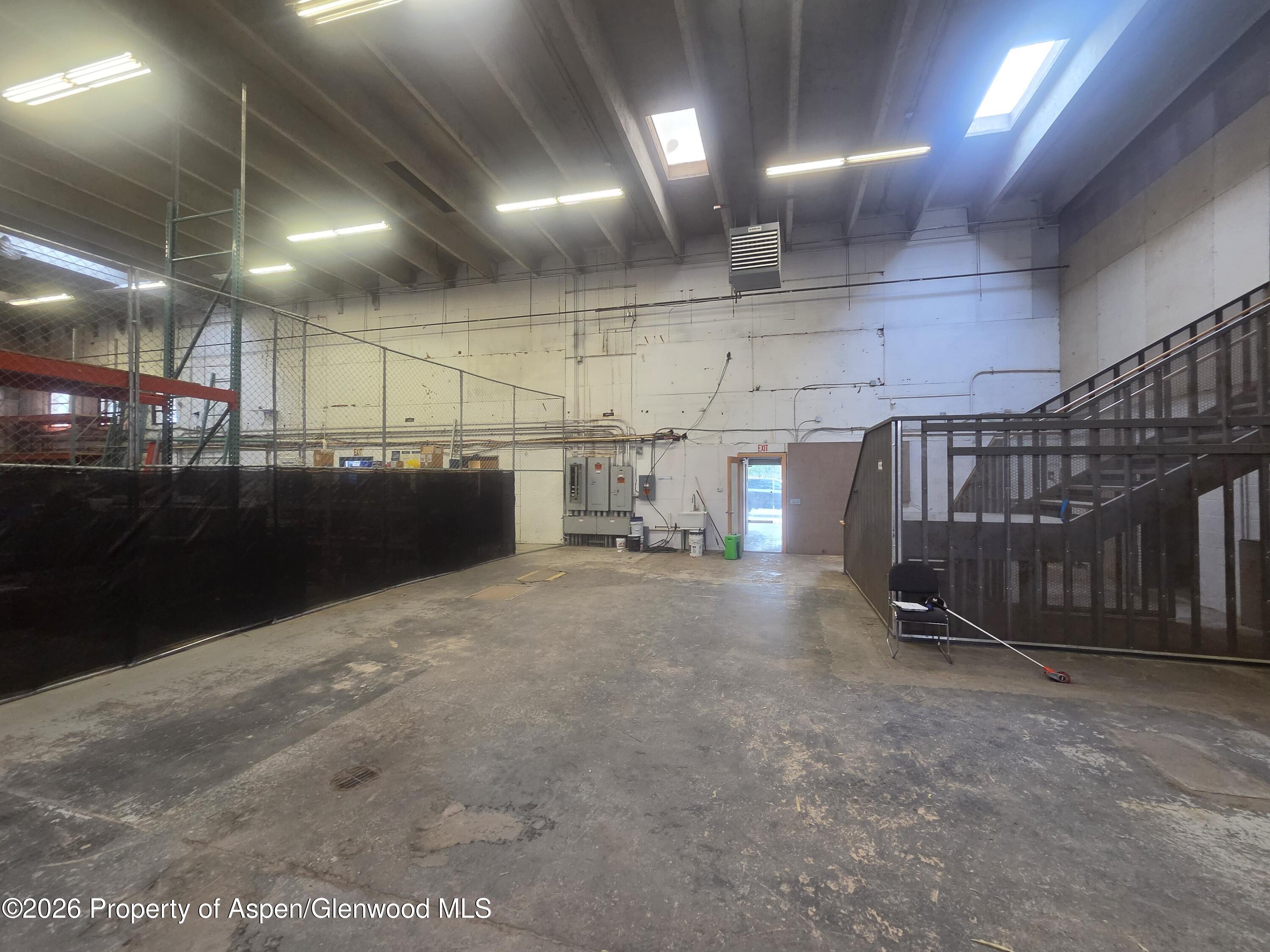 Industrial interior with chain-link enclosures, a metal staircase, and a worn concrete floor.