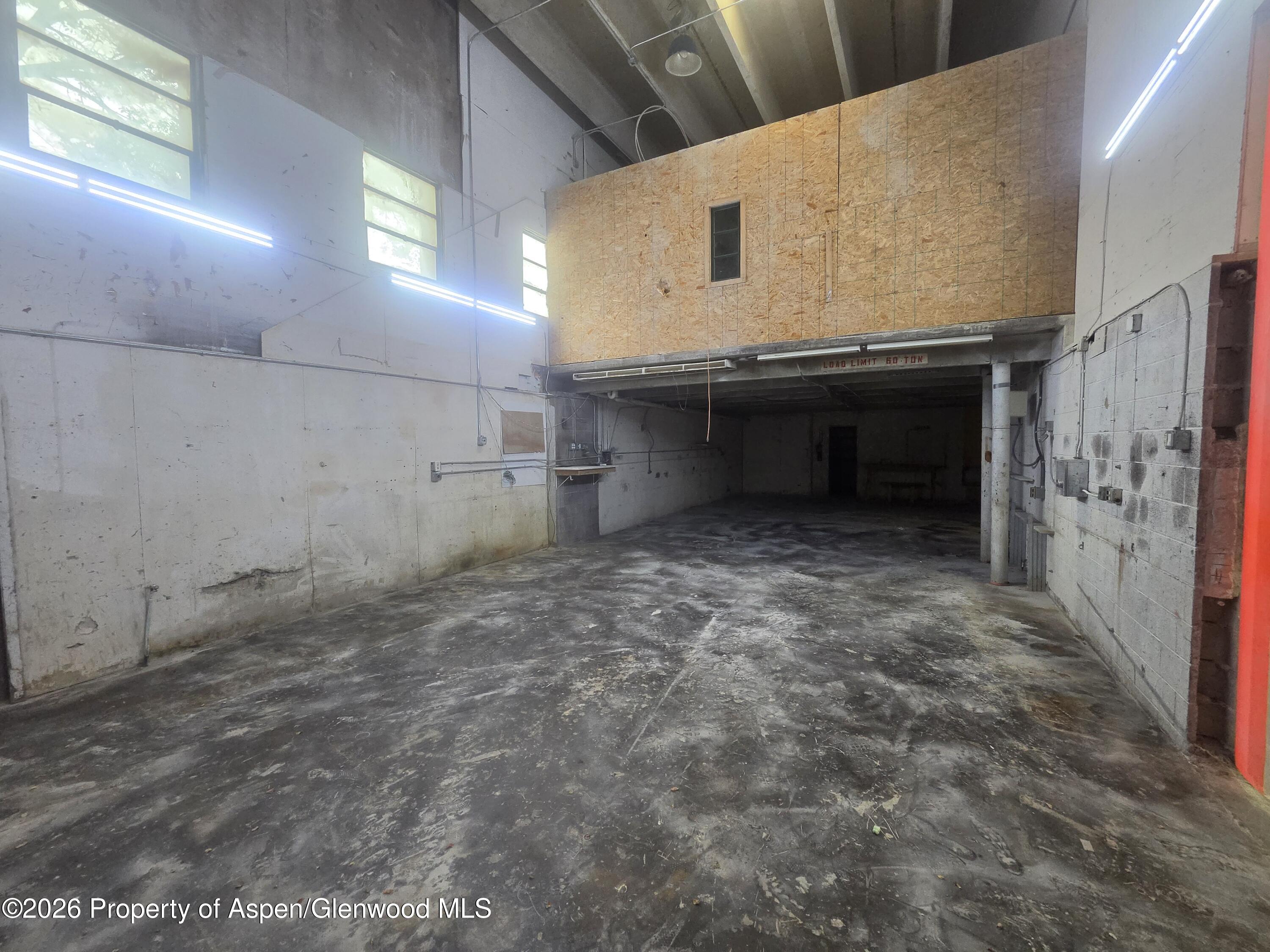 Vacant industrial workshop with a concrete floor and a large plywood mezzanine.