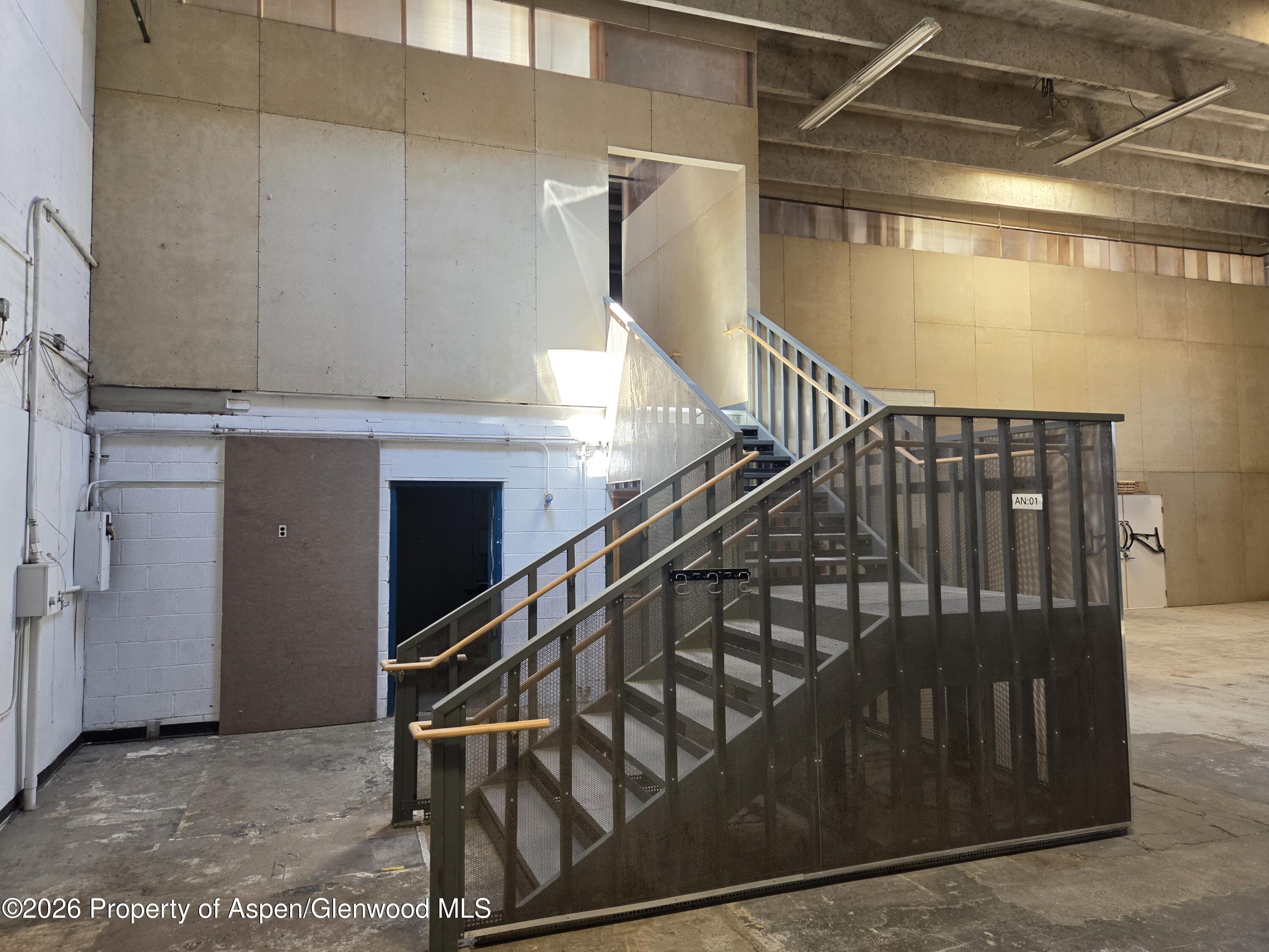Industrial staircase with dark mesh railings in a vacant commercial interior.