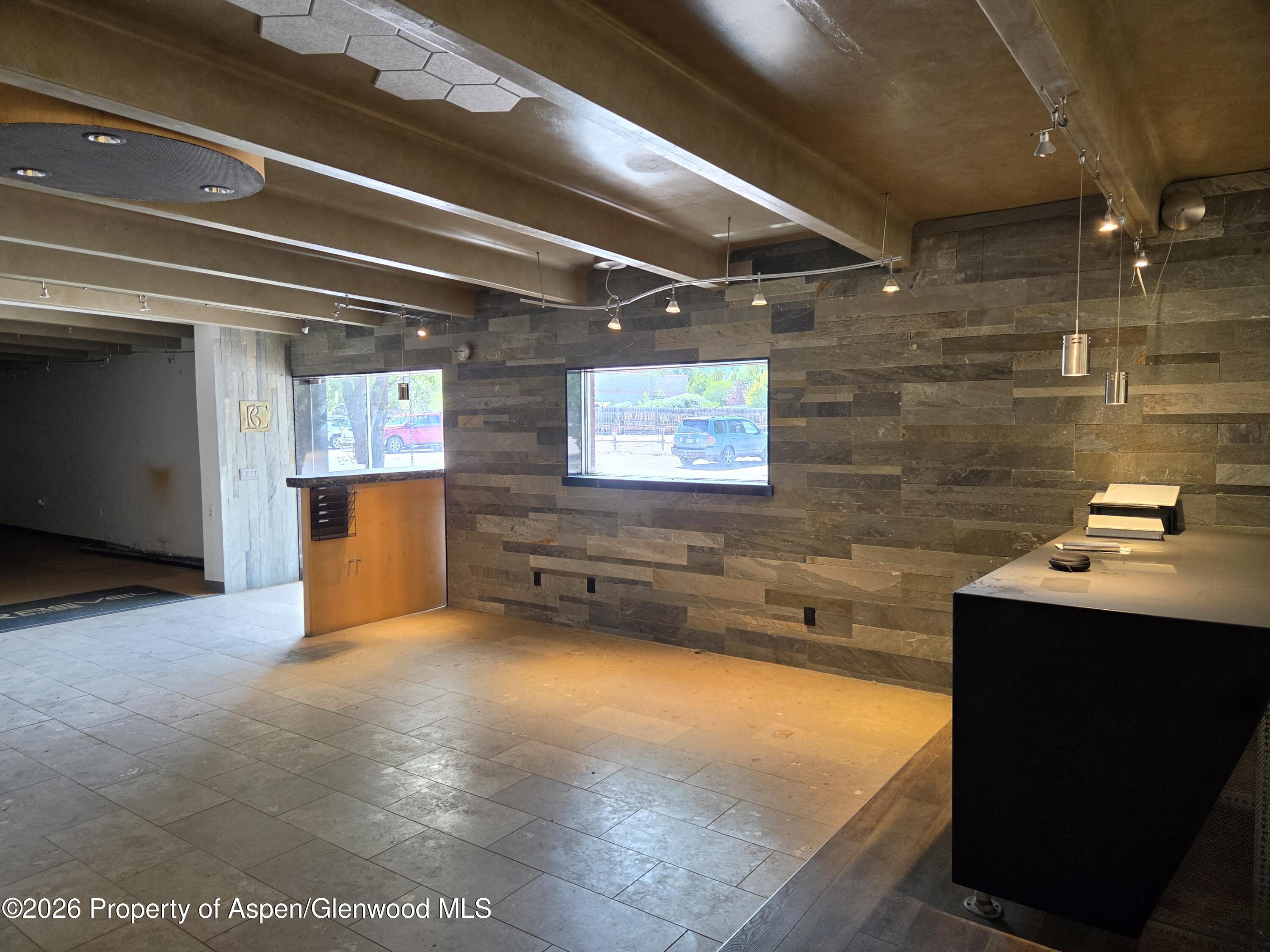 Commercial interior with stone walls, street-facing windows, and wood-front reception counter.