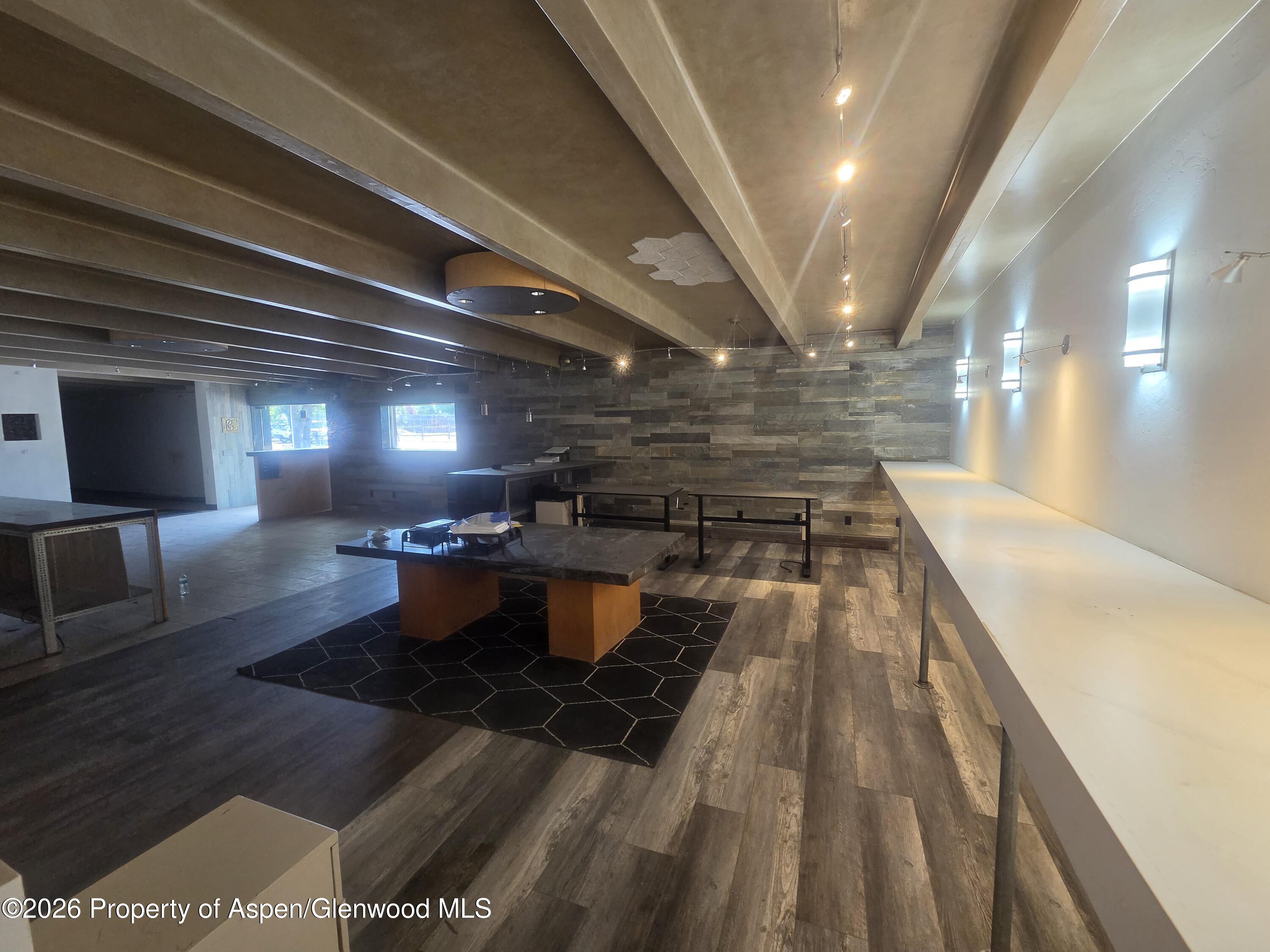 Vacant commercial interior with a long white counter, dark stone wall, and central display tables.