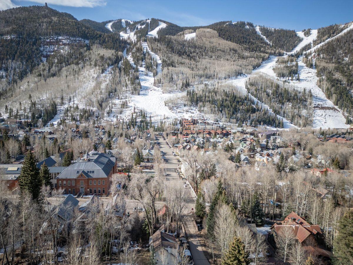 Aerial view of Telluride beneath forested mountains with snow-covered ski runs.