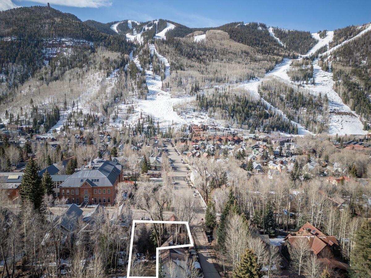 Aerial view of a Telluride neighborhood, with the property outlined beneath snow-covered mountain ski runs.