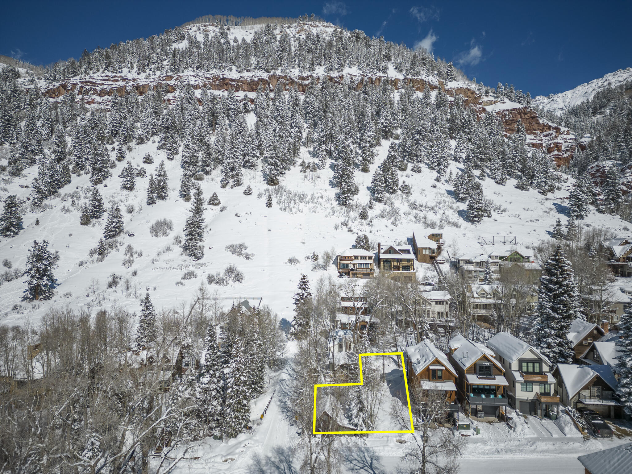 Aerial view of the 475/477 W Galena Avenue lot outlined in yellow beneath a snowy mountain.