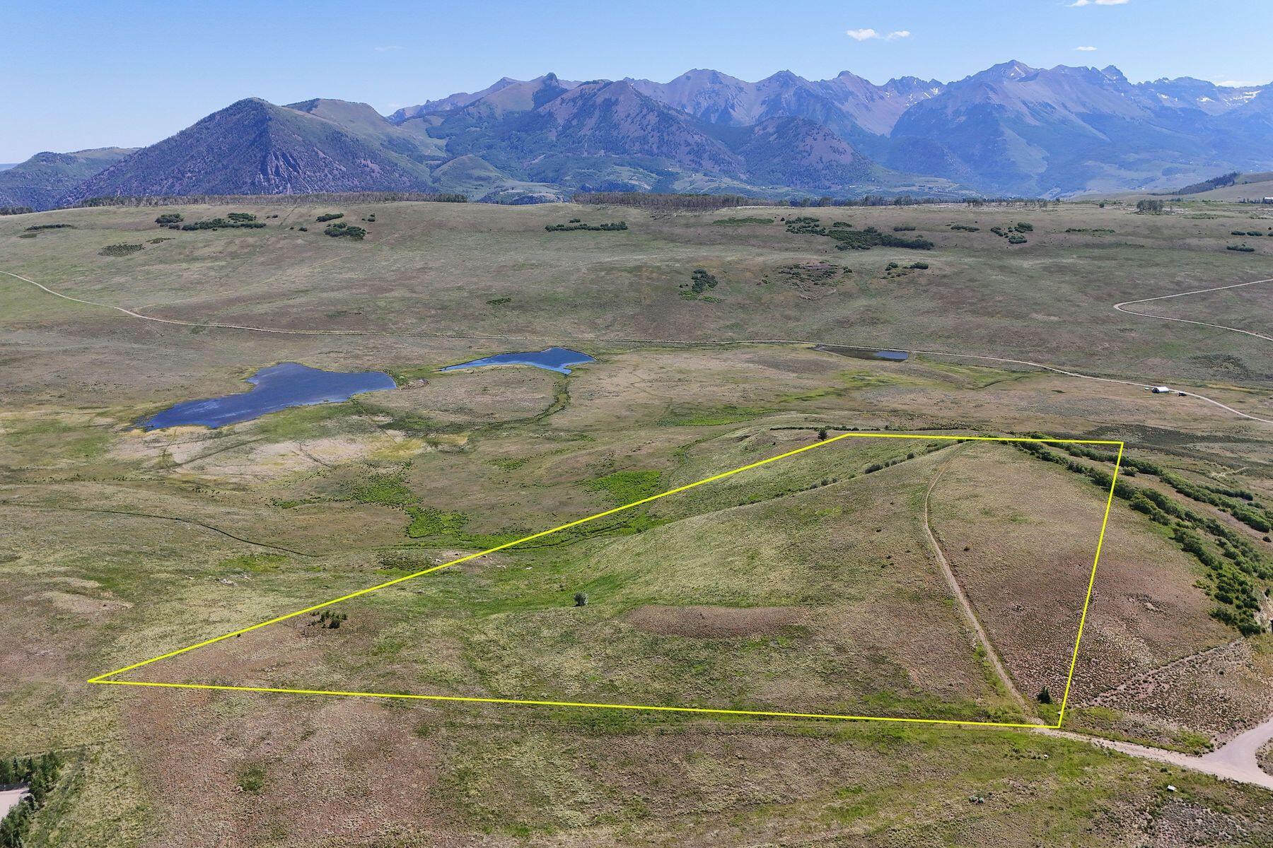 Vacant open-land parcel outlined in yellow, with ponds and a mountain range beyond.
